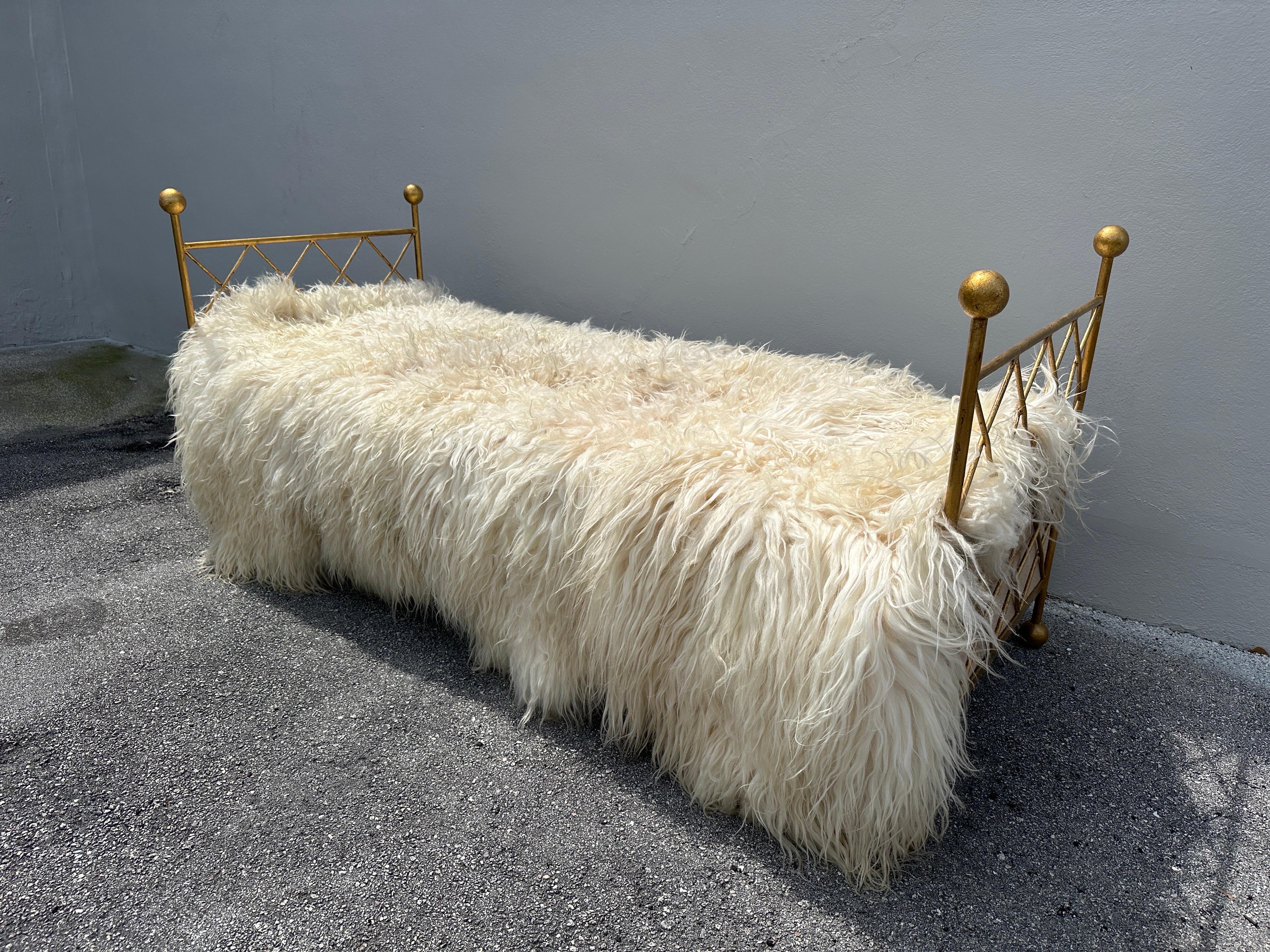A solid iron frame with lovely gold gilding, accented by orb finials and feet, crisscross side panels.  Newly upholstered fabric bed cushion and box below.  The oversized Mongolian wool throw is just for photo-purposes, available for sale separately