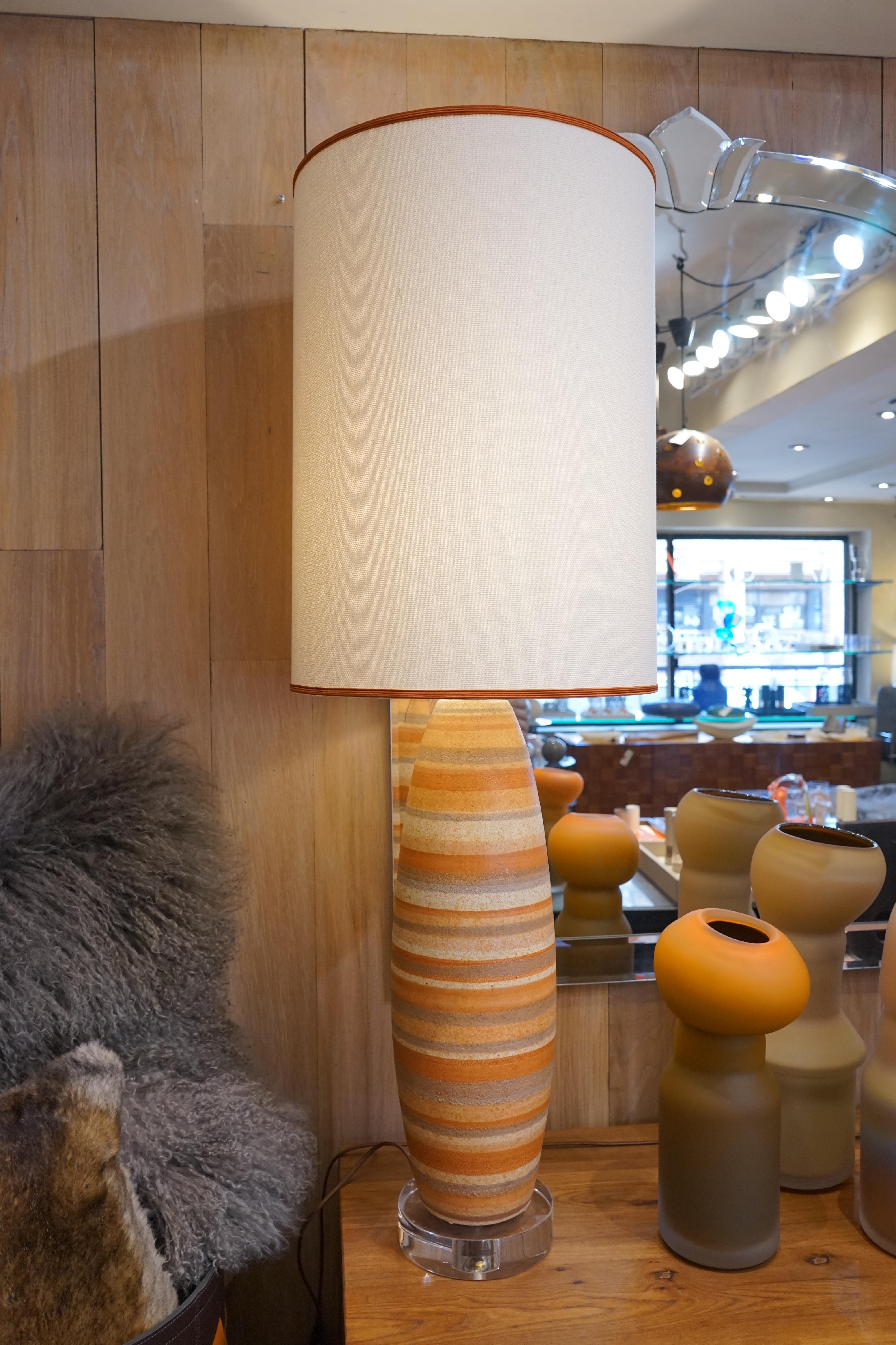 1980s French pair of striped pottery lamps with orange, grey, and beige stripes and custom lampshades. Lucite bases add to the design of these unique lamps.