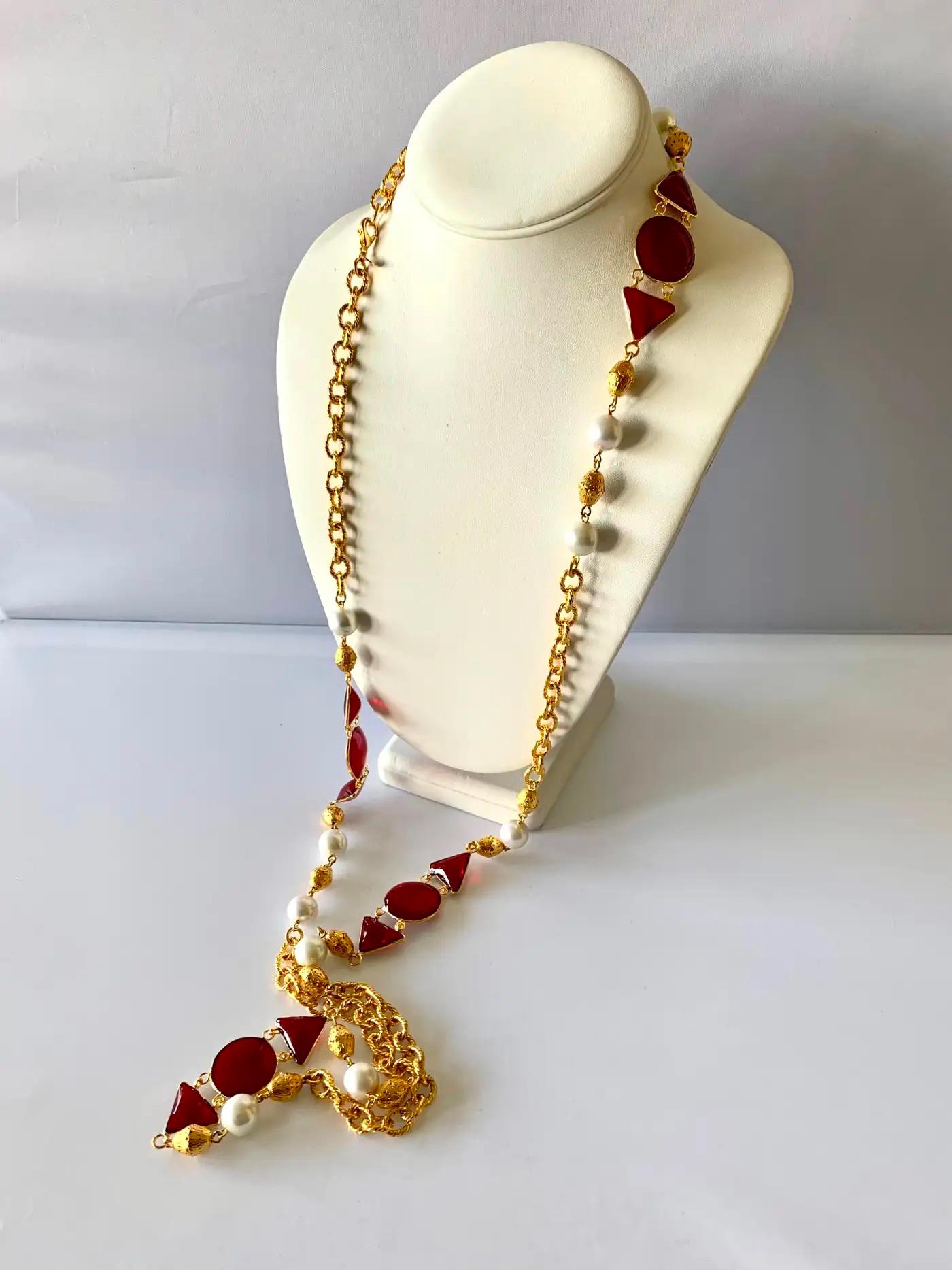 French sautoir comprised of an ornate gilt metal chain accented by white faux pearls and red geometric gripoix and pate de verre elements. The necklace can be doubled.

Length: 51 inches