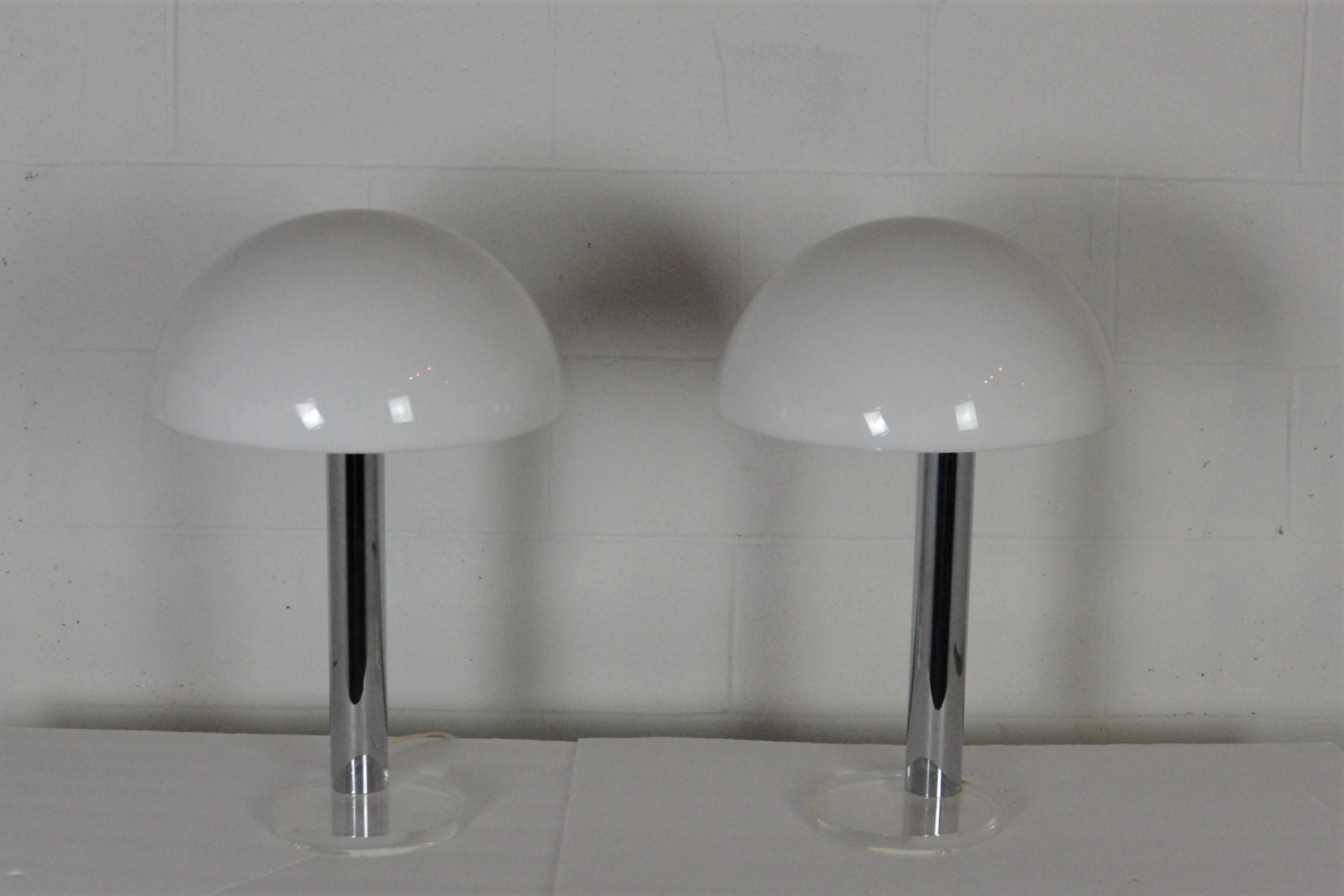 A pair of gage Cauchois chrome and Lucite table lamp. The three-way dimmer is touch-controlled on the brass stem. Lucite base and exposed bulb with a frosted Lucite dome.