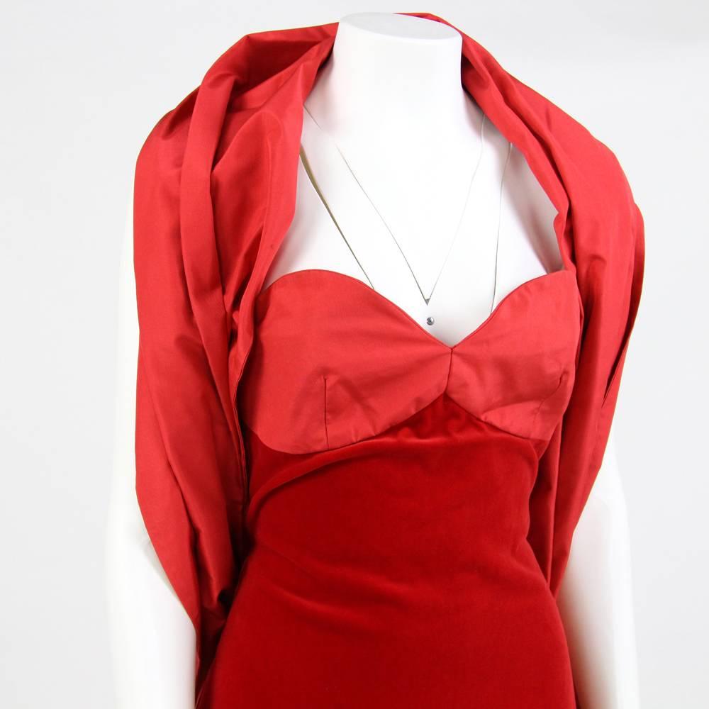 Long princely Gambaretto red velvet dress with sweetheart neckline in contrasting fabric. It features three red ribbons that end with a bow, two of them follows the lateral stitchings from the armpits to the hips while the third covers the zipper on