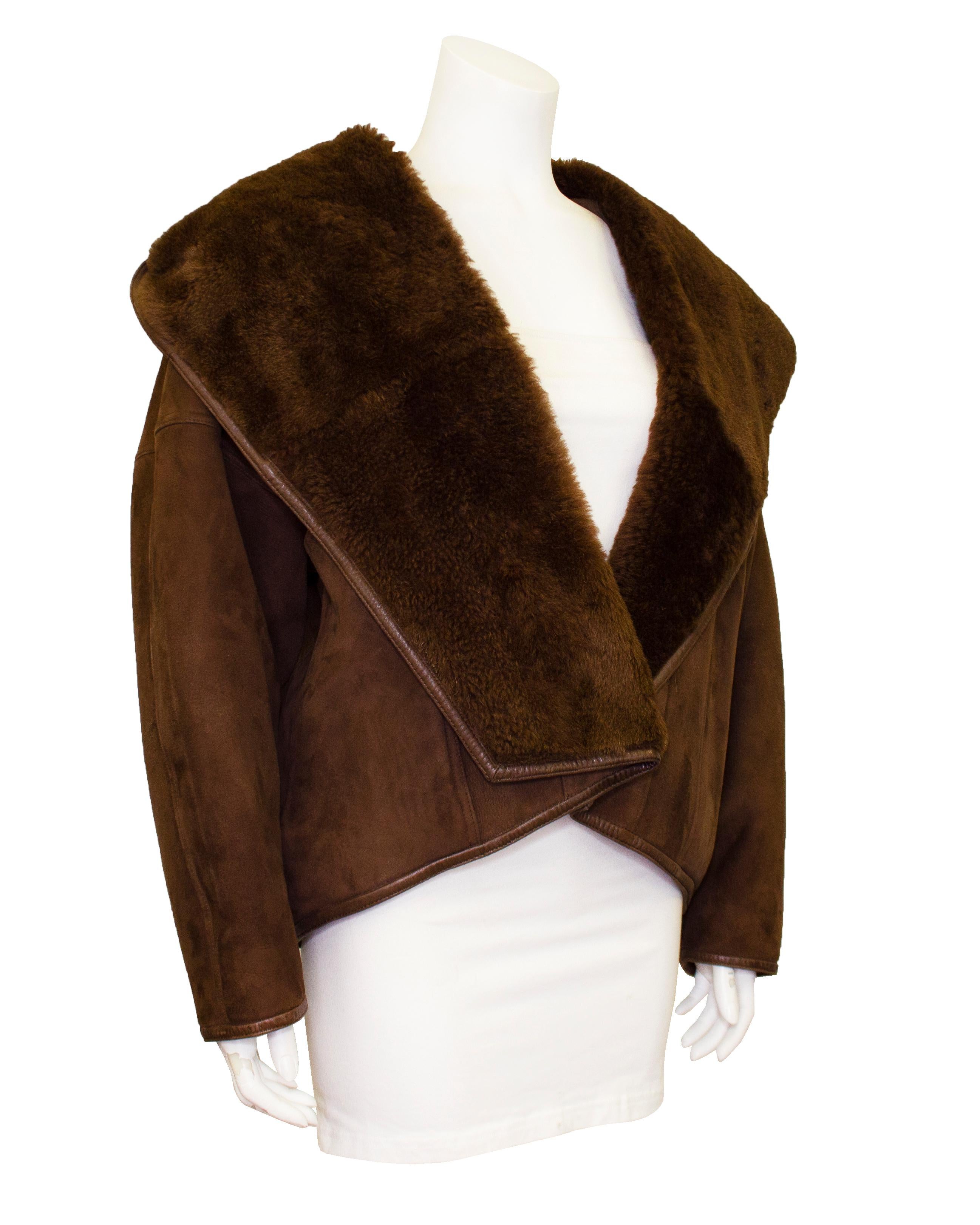 Incredible Genny bomber jacket from the 1980s. Chocolate brown suede outer with shearling interior. Shawl collar that cascades into a large hood and dolman sleeves. Single button closure at hip and oversized open slit pockets. Excellent vintage