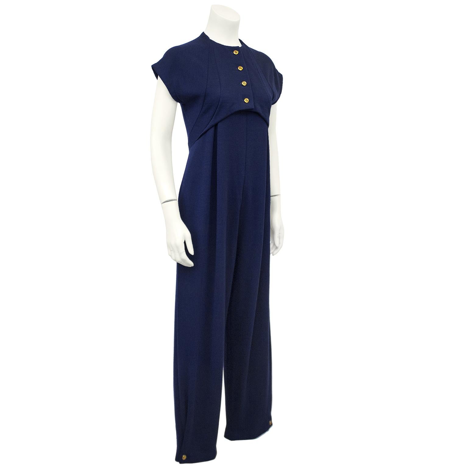 Cap sleeved Geoffrey Beene navy wool jersey blend jumpsuit from the 1980s. The overlaying top has gold buttons down the front and appears like a cropped bolero with curved seams down the sides and hits just below the breast bone. The body of the