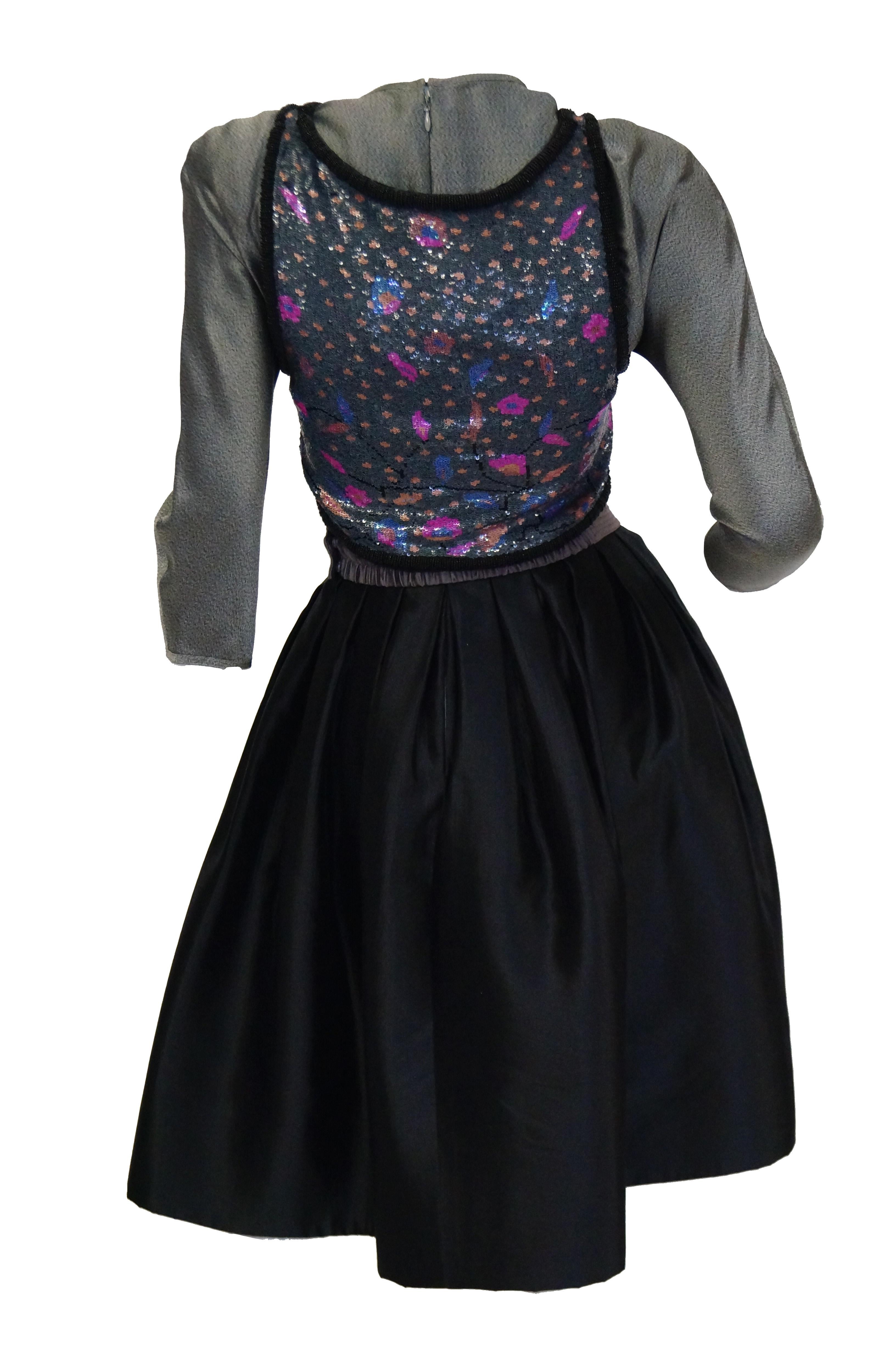 Striking three - piece ensemble by Geoffrey Beene. The ensemble includes a cocktail dress with full knee - length skirt in black, and grey silk long sleeve top with round neckline. A grey - lavender cummerbund belt with quilted accent stitching