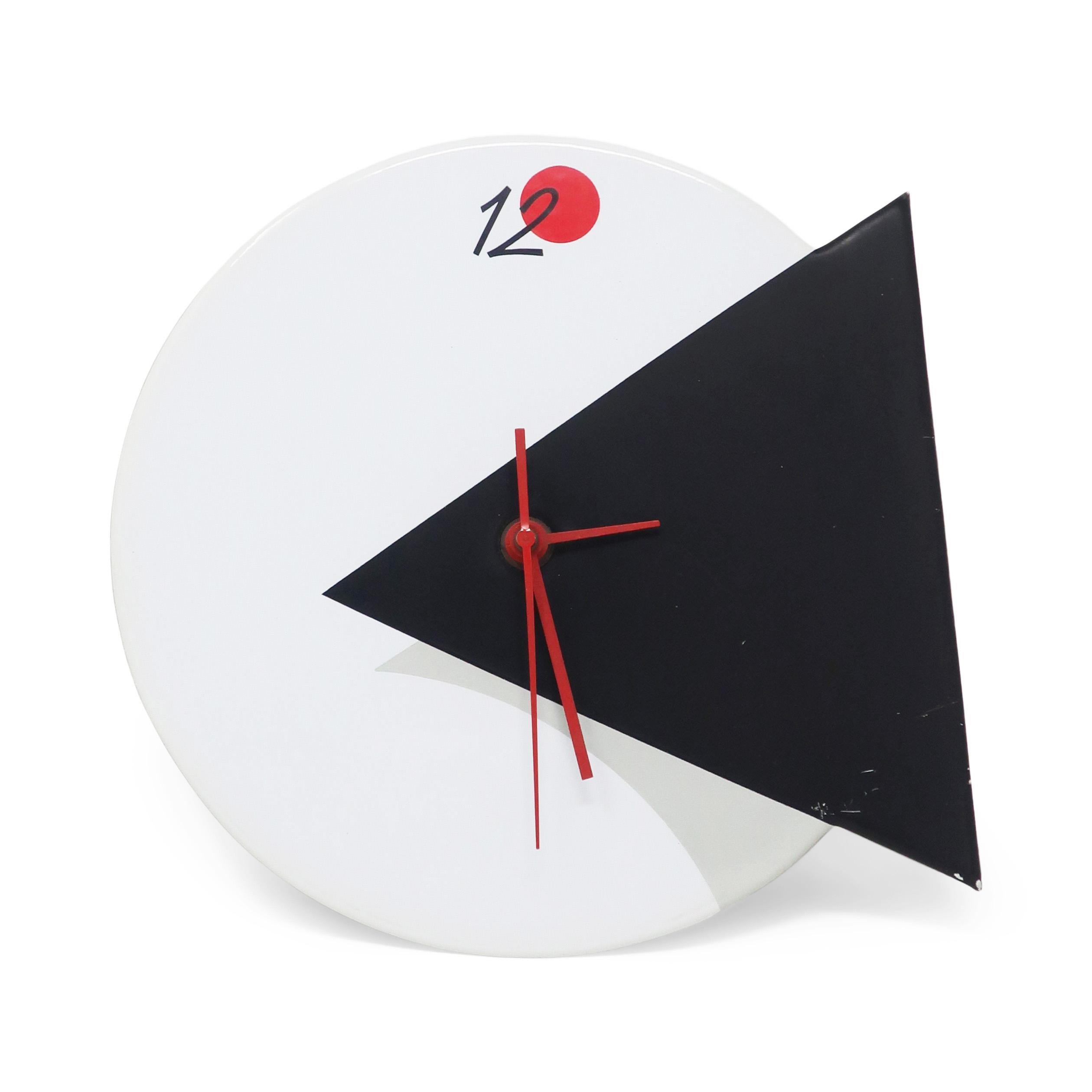 A striking postmodern, Memphis-inspired wall clock by Small World Greetings. White vinyl face with inset black triangle, light gray shadow, red hands, and red circle and 