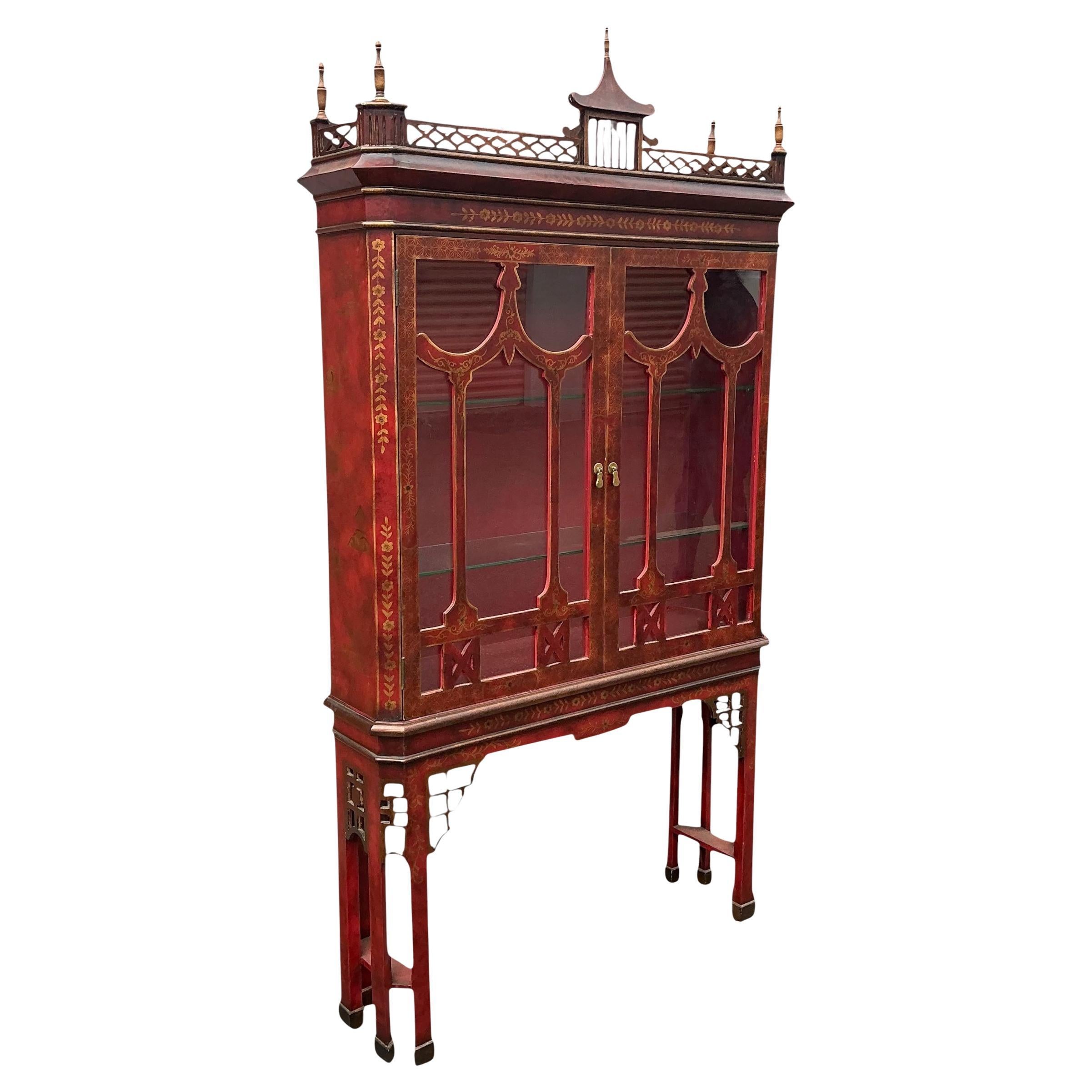 This is a Georgian Chinese Chippendale style red and gilt painted display cabinet or vitrine. It is two pieces with two adjustable interior glass shelves. The pieces has elaborate fretwork highlighted with gilt chinoiserie details on a red