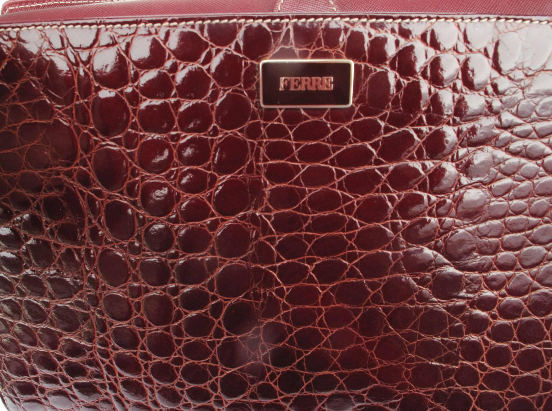 Dip red patent leather shoulder bag with crocodile embossing on the front. Golden metal hardware, closes with a magnet button, it has  three compartments with a zip pocket, silver-fabric lining with logo pattern. Long strap (125 cm) adjustable with