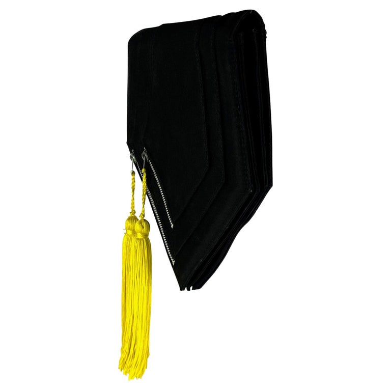 TheRealList presents: a black fabric Gianni Versace clutch, designed by Gianni Versace. From the late 1980s, this hexagon flap clutch features two exterior pockets with yellow tassel zipper accents. A fabulous piece of early Versace, this clutch is