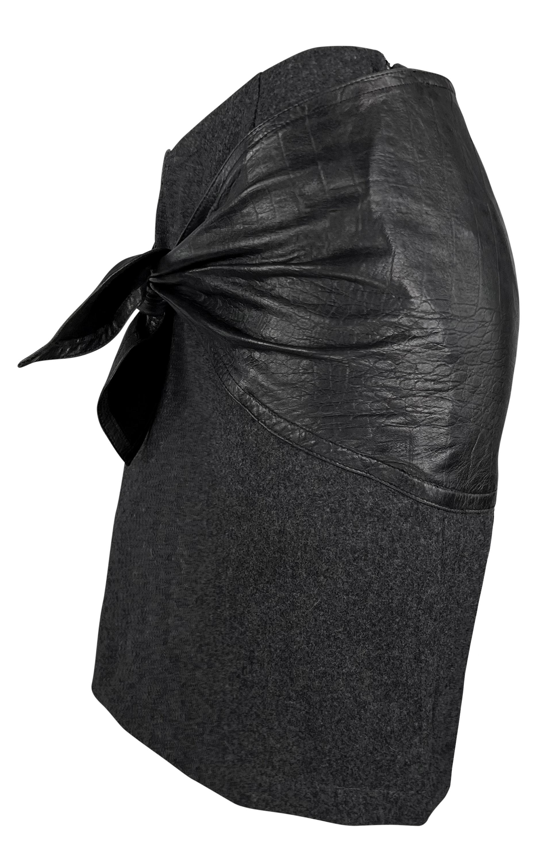 This grey Gianni Versace mini skirt from the 1980s features a unique crocodile-embossed leather tie that elegantly cinches the hips. A vintage find, this piece reflects the signature style of Versace's early designs, bringing a classic touch to any
