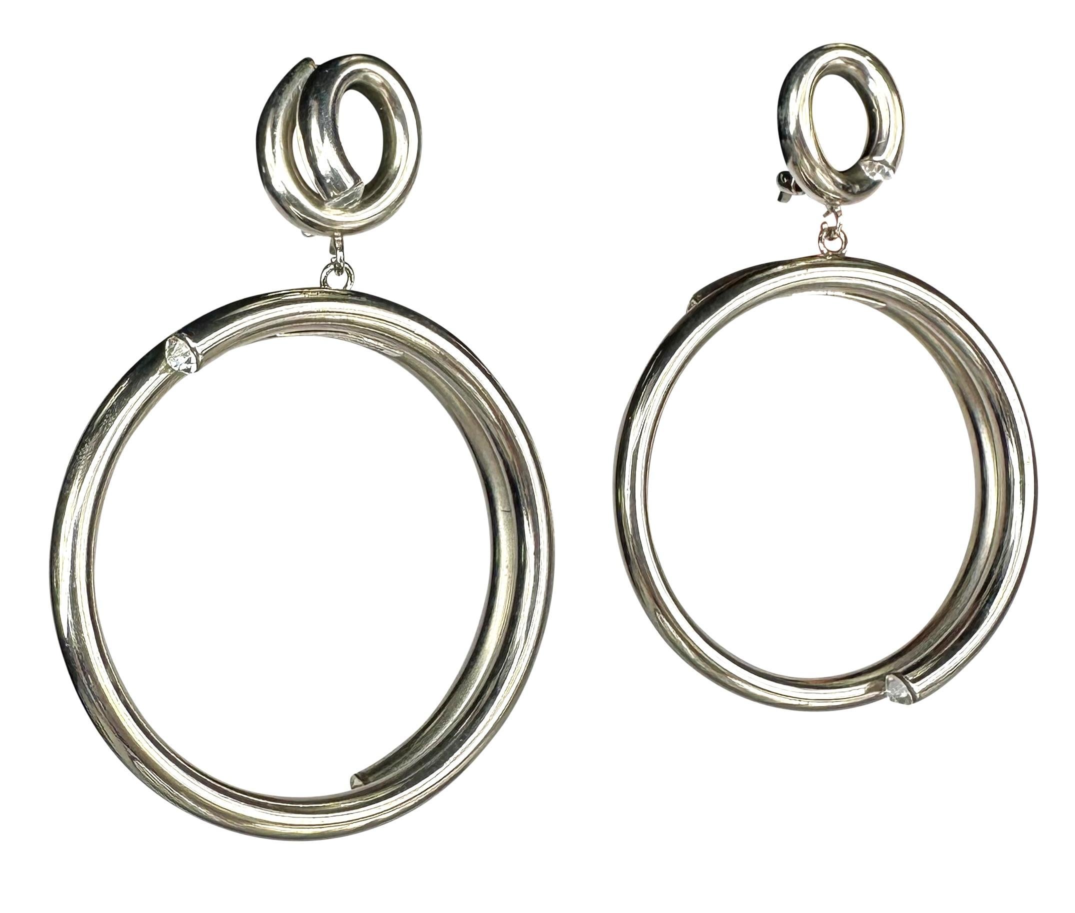 Presenting a pair of silvertone Gianni Versace costume hoop clip-on earrings. From the 1980s, these fabulous earrings feature a circular coil drop accented with rhinestones at each end. A rare find from the early days of Gianni Versace, these modern