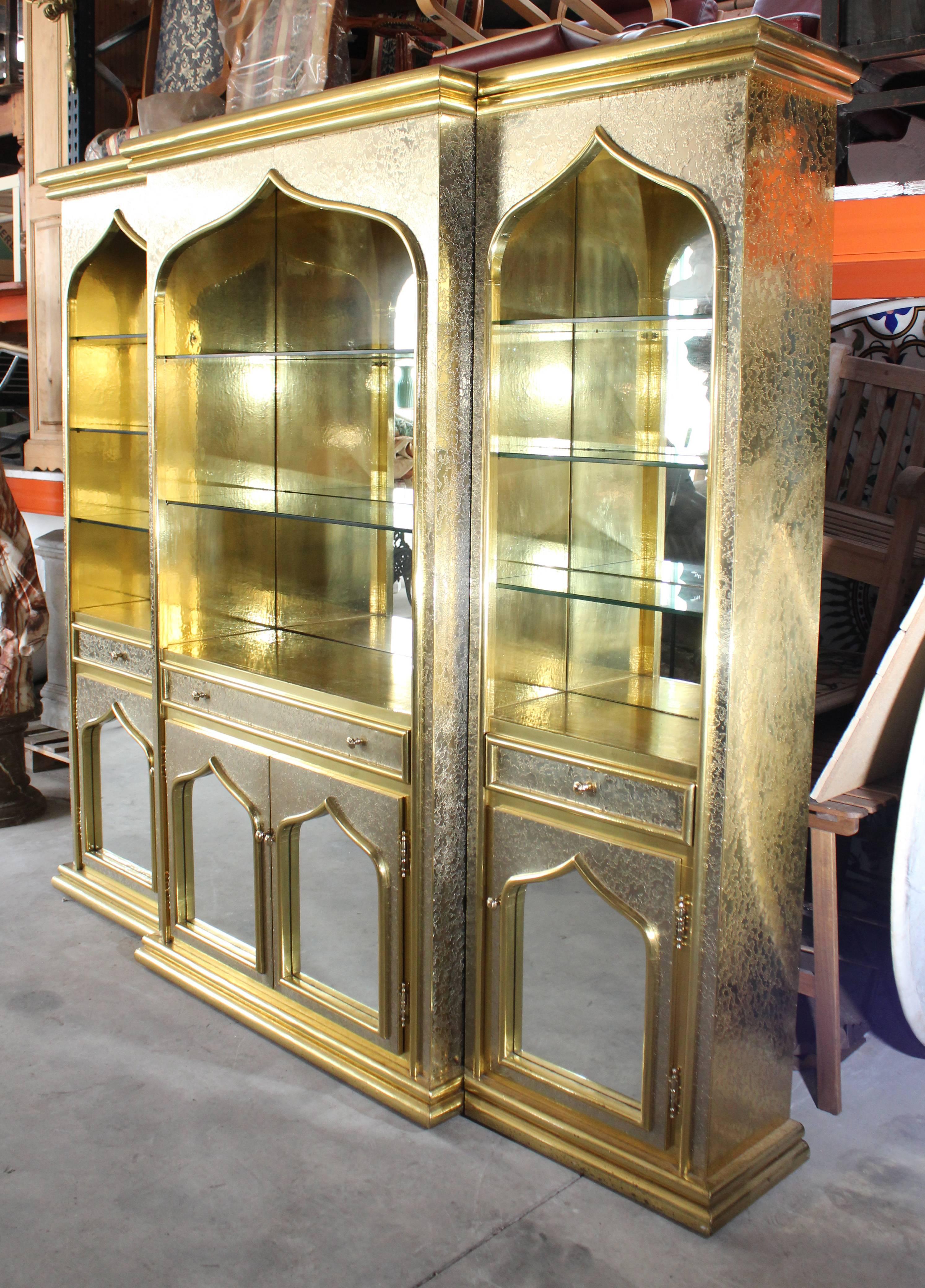 Grandiose 1980s gilded brass panels and mirrors over a wooden frame library, with cabinets below and light fittings on the shelves. 

A top quality piece signed by Gony Nava, a renowned local craftsman working in the Arabic inspired style of