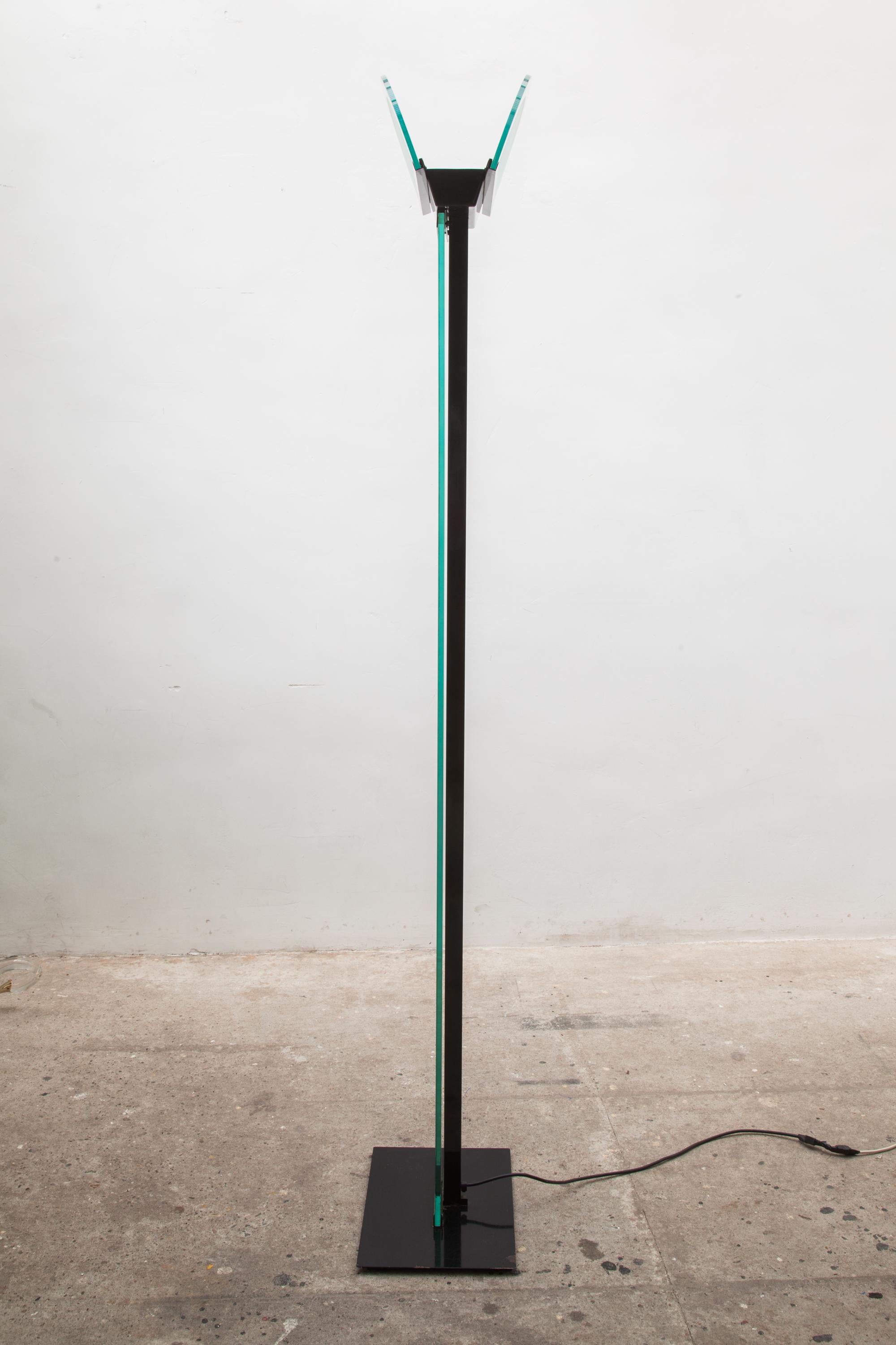 A 1980s torchiere lamp in black metal and glass. Frosted shade. Memphis style design. Measures: height: 165 cm shade width: 35 cm.
 