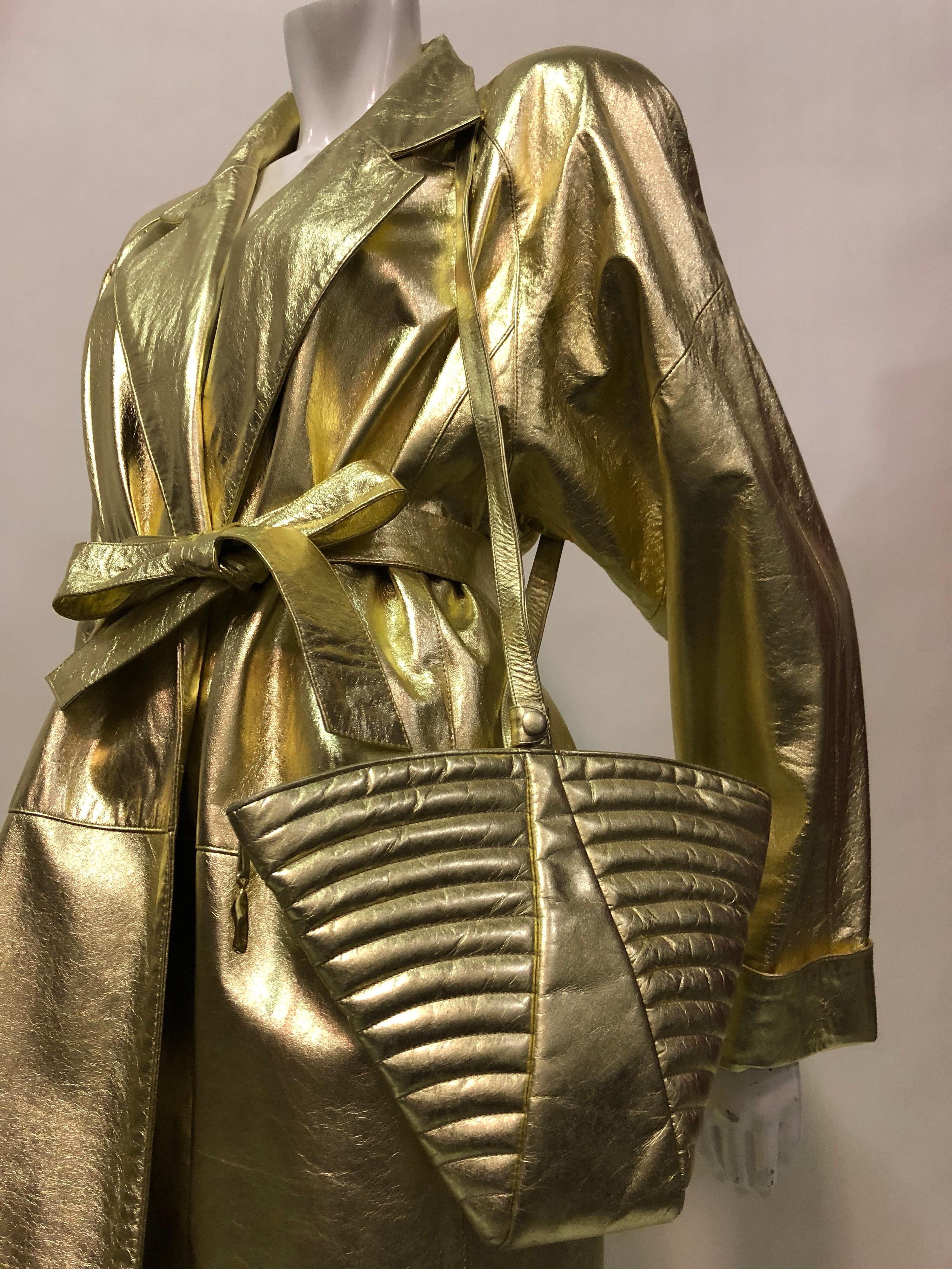 A dazzling 1980s gold leather ensemble:  a gold leather trench coat by Evan Arpelli with original belt, dramatic notched collar and strong sculpted shoulder silhouette. Paired with an original 1980s Maud Frizon Art Deco-inspired quilted gold leather