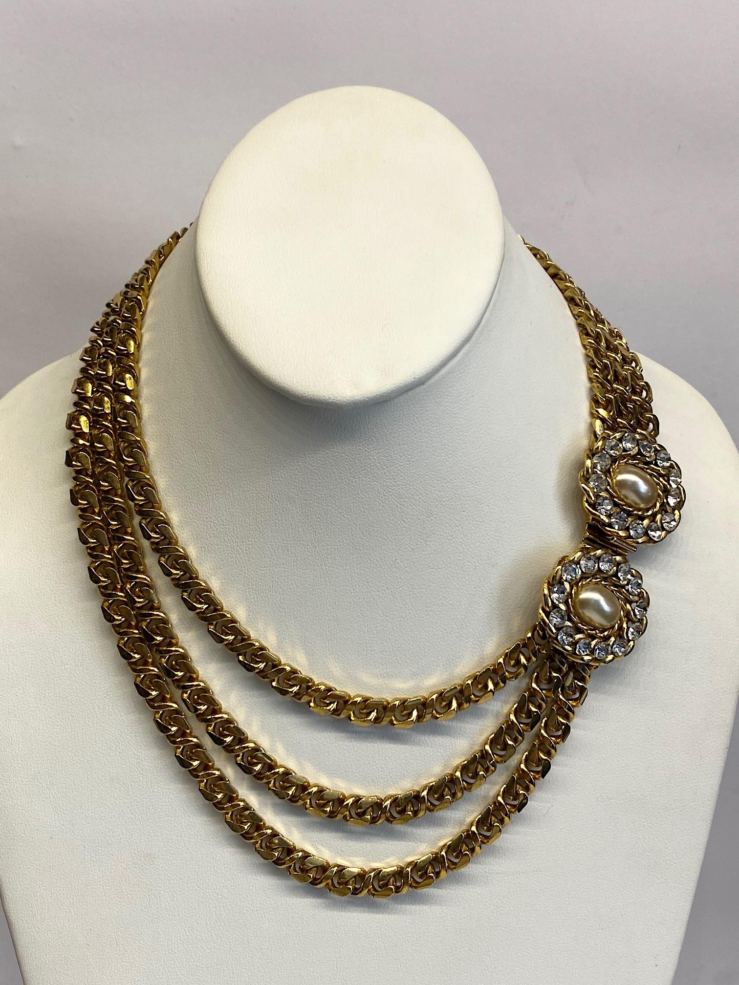 1980s three strand curb link chain necklace with large clasp. Each of the three strands of chain measure .25 on an inch wide and .13 of an inch thick. The large push pin box clasp is comprised of two matching oval medallions 1.13 inches wide and