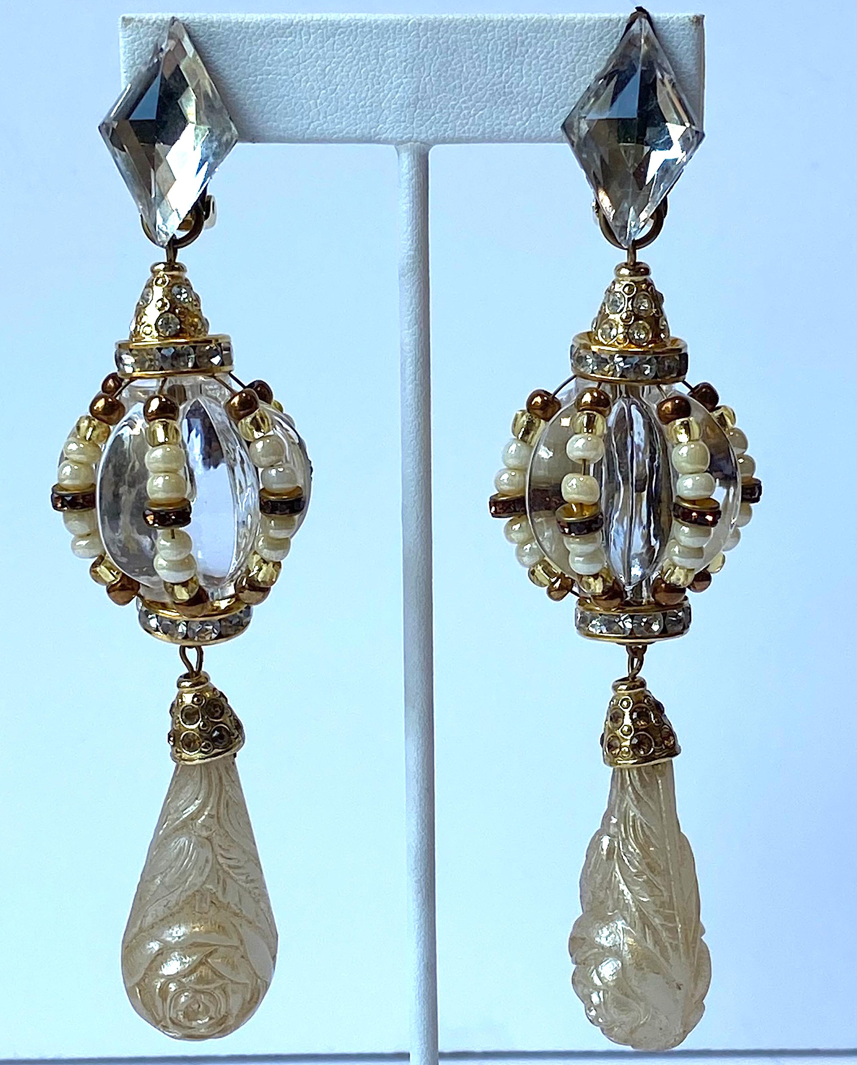 A true pair of statement earrings from the 1980s. Each measures 1.13 inches in diameter and 4.5 inches long. The earrings have a lucite faceted diamond top piece with clip back. Suspended from it is gold rhinestone cone on a rhinestone rondel and