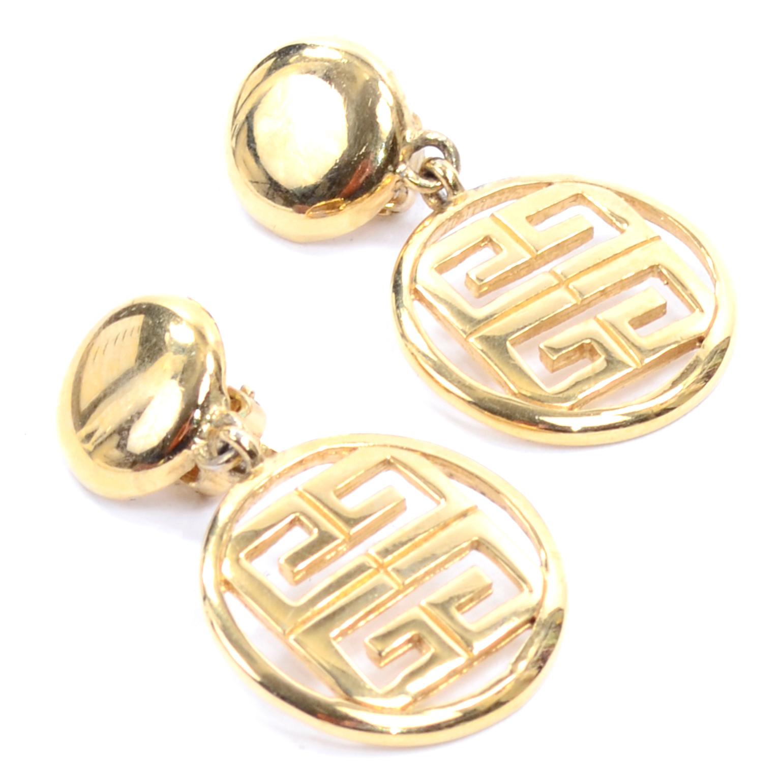 Beautiful gold tone Givenchy logo clip on dangle drop earrings. These great designer earrings  have a solid circular piece that clips to the ear, with a drop circle containing the cutout Givenchy logo. They are marked 