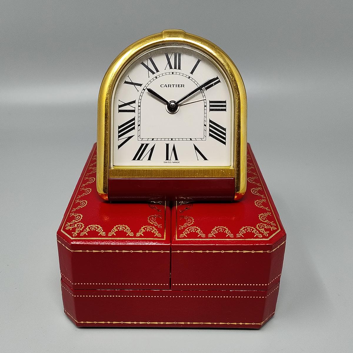 1980s Gorgeous Cartier Romane alarm clock pendulette. Made in Swiss. It's in gold plated 18K. White enamel dial. Clock case numbered 66021 . With case, lined with red leather, instructions and certificate. It works perfeclty and is in excellent