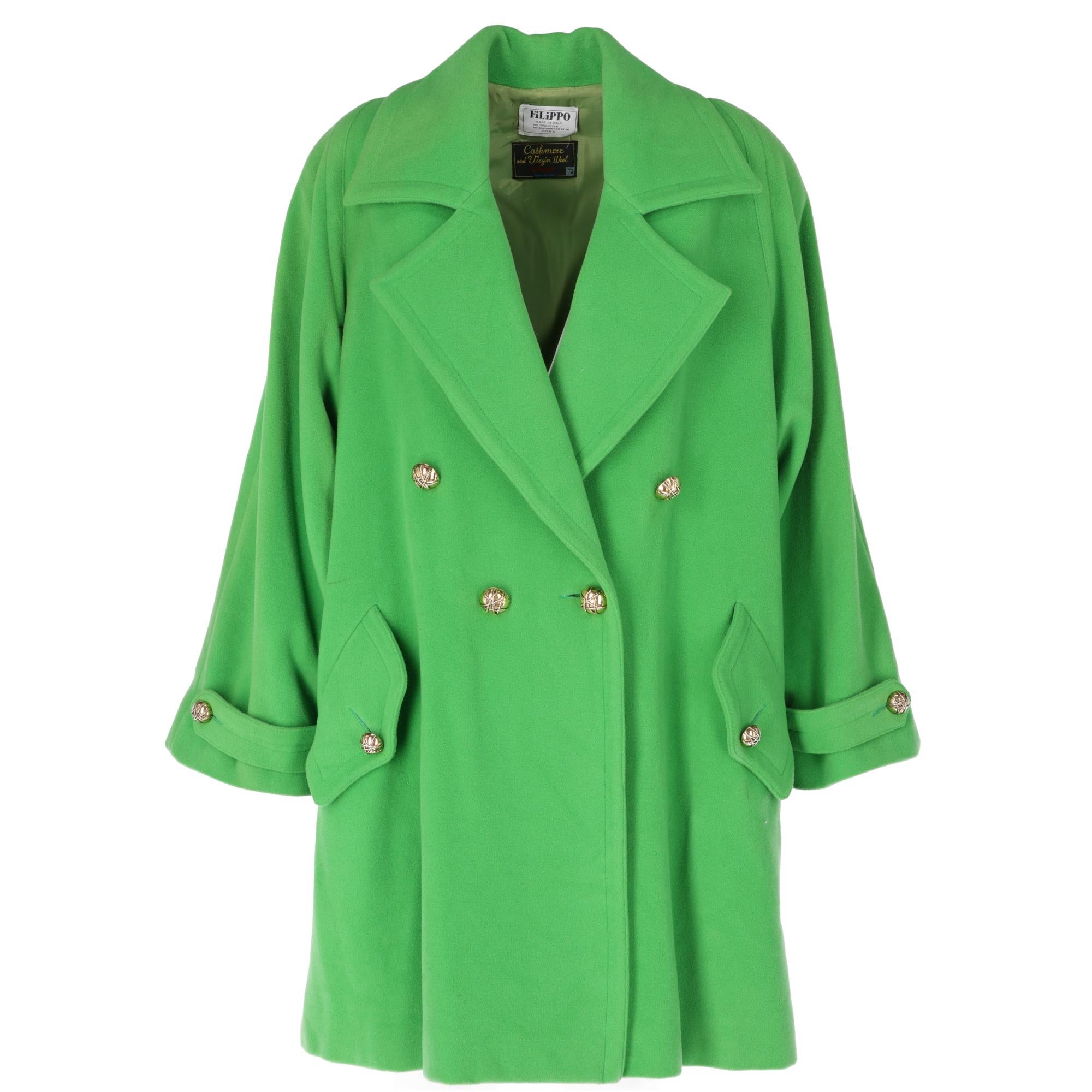 Grass-green coat with classic lapels collar, double-breasted front closure with golden hemispherical buttons, padded shoulders, long sleeves with buckle and button, two side pockets with flap and button, belt, rainproof cape on the back and slit.