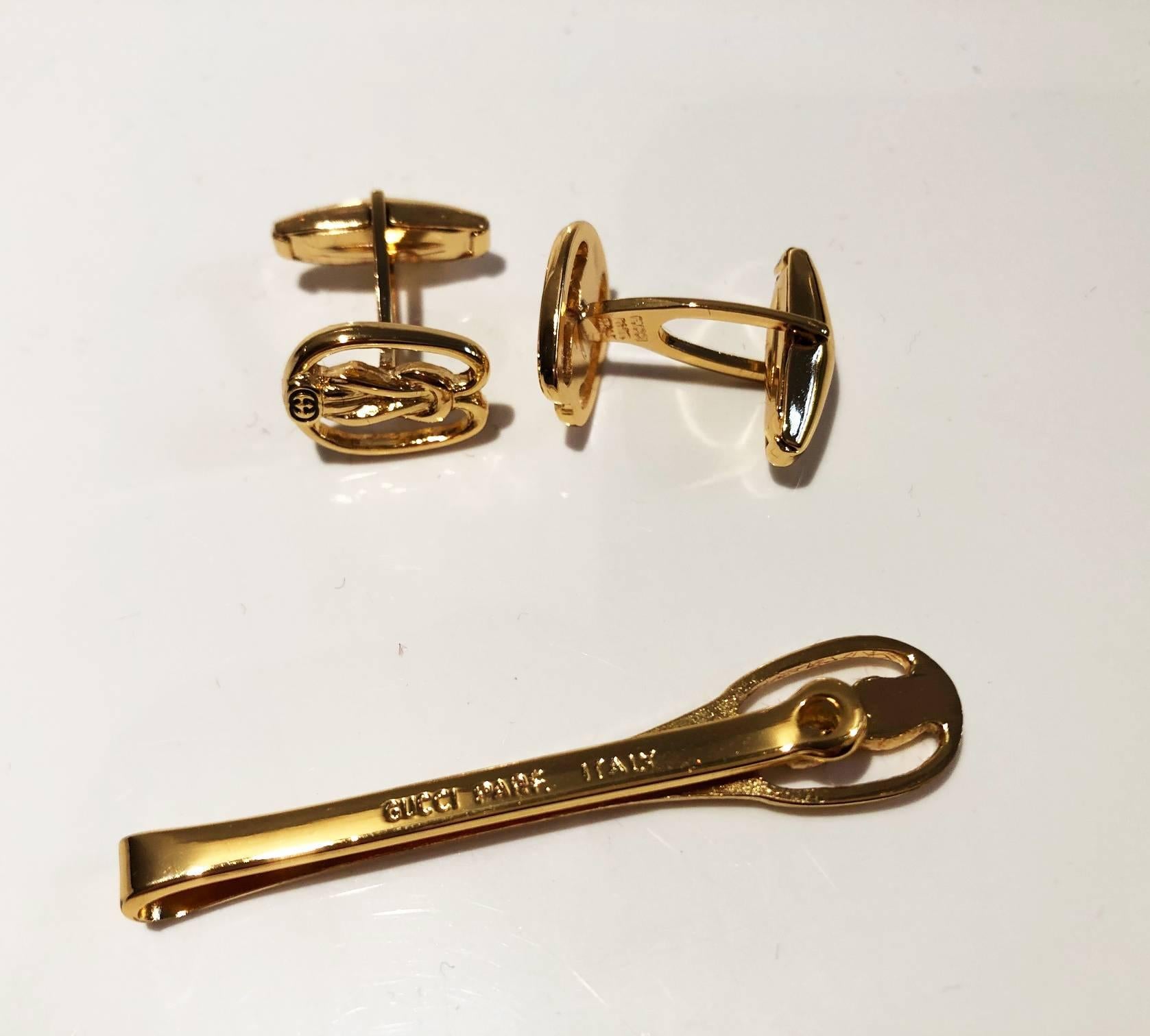 Vintage Signed Gucci cufflink and tie clip set in gold tone, GG interlocking logo on black background, stylish set for both men and women 
 
Measurements: Cufflink heads measure approx. 1.5cm x 1.2cm at their widest point; Tie clip measures approx.