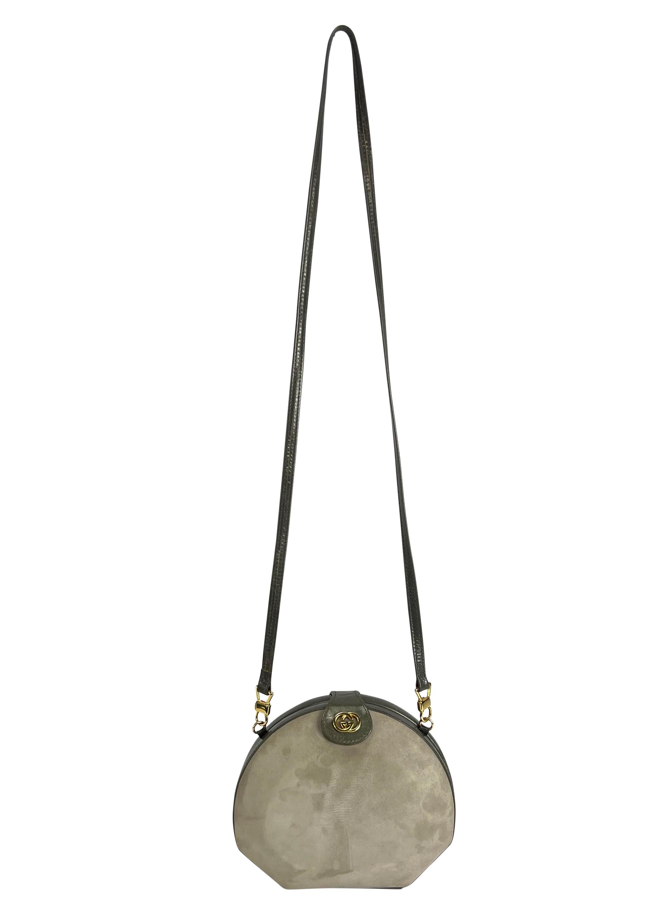 Presenting a fabulous grey suede hardshell Gucci convertible crossbody bag. From the 1980s, this clam shell style bag is constructed in a light grey suede contrasted with a darker grey leather at the closure, strap, and flap. The crossbody strap can
