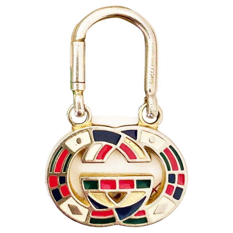 This elegant Gucci Keyring features a light gold-tone metal frame, masterfully adorned with multi-hued enameling and the iconic interlocking logo emblematic of the brand.

Condition: 1980s, vintage, very good, minimal sign of wear 

Dimensions: