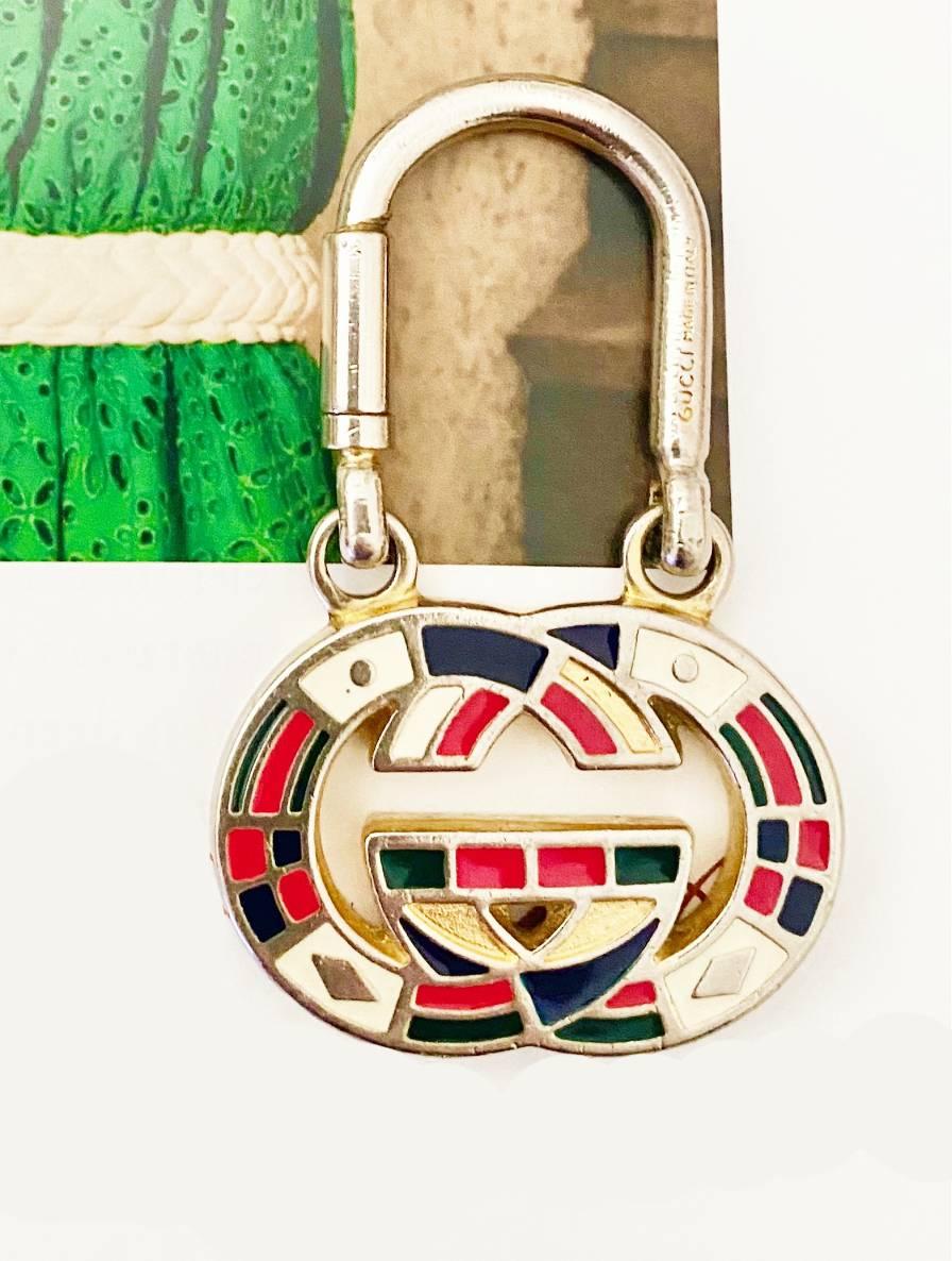 This elegant Gucci Tom Ford Era Keyring features a light gold-tone metal frame, masterfully adorned with multi-hued enameling and the iconic interlocking logo emblematic of the brand.

Condition: 1980s, vintage, very good, minimal sign of wear