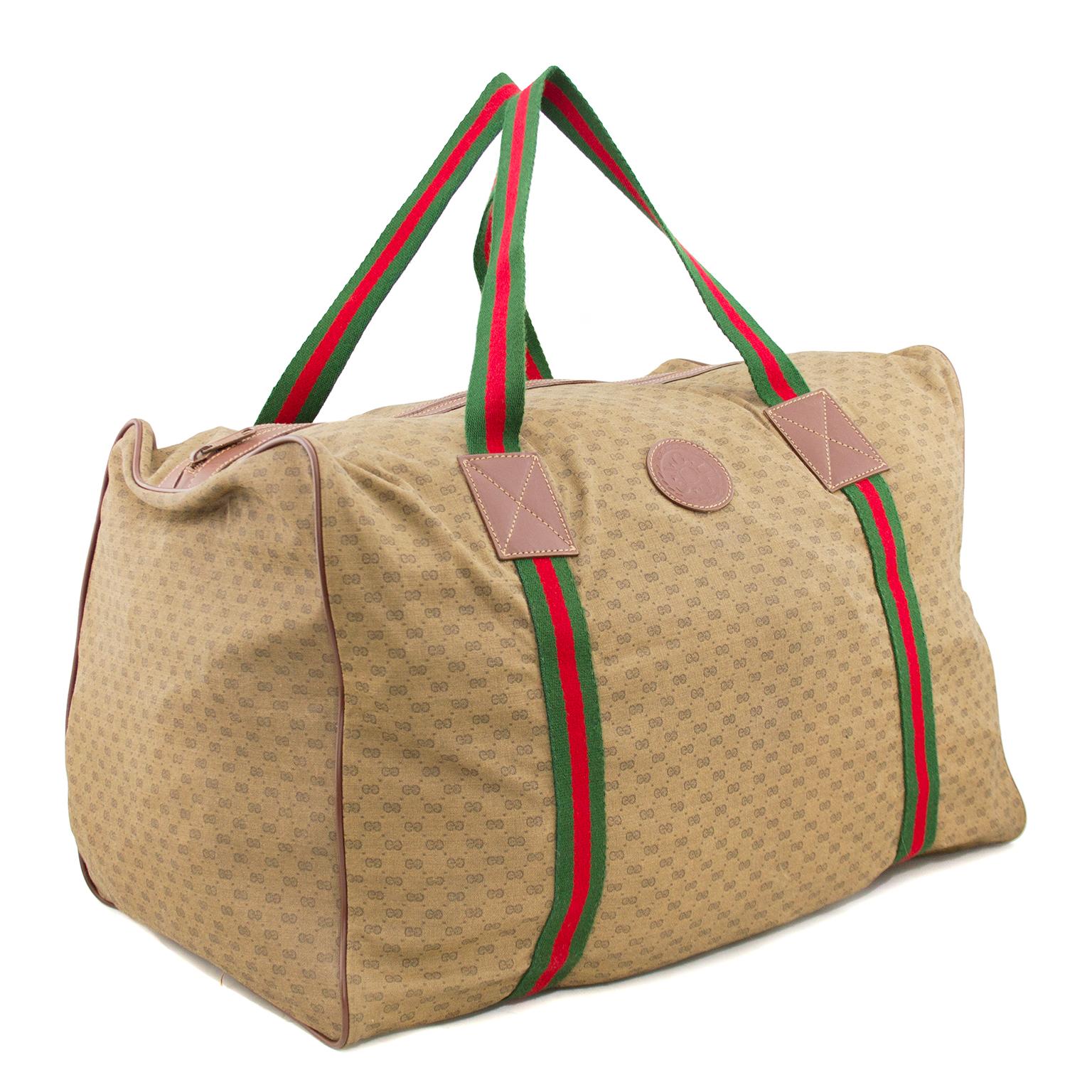 Gucci brown coated nylon monogram duffle bag from the 1980s. The bag is trimmed in brown leather and features iconic green and red striped straps that wrap around the bottom of the bag. Zipper across the top, no interior pockets. The fabric is very