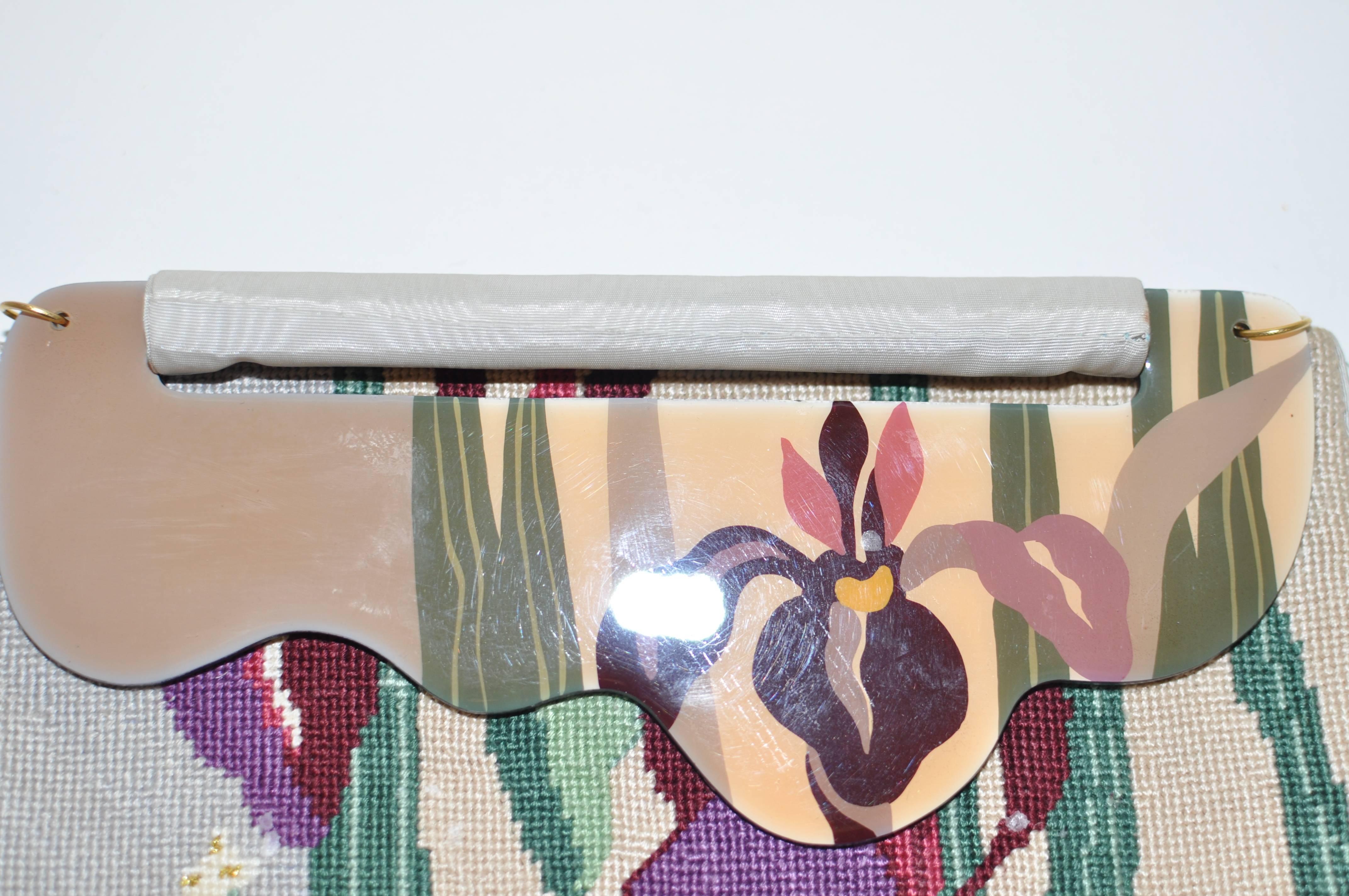 Delightful bag! Petit point on the front with a hand painted plastic/lucite flap with a back and lining in moire. The design is floral and there are loops for a strap. The inside lining has a slot pocket.