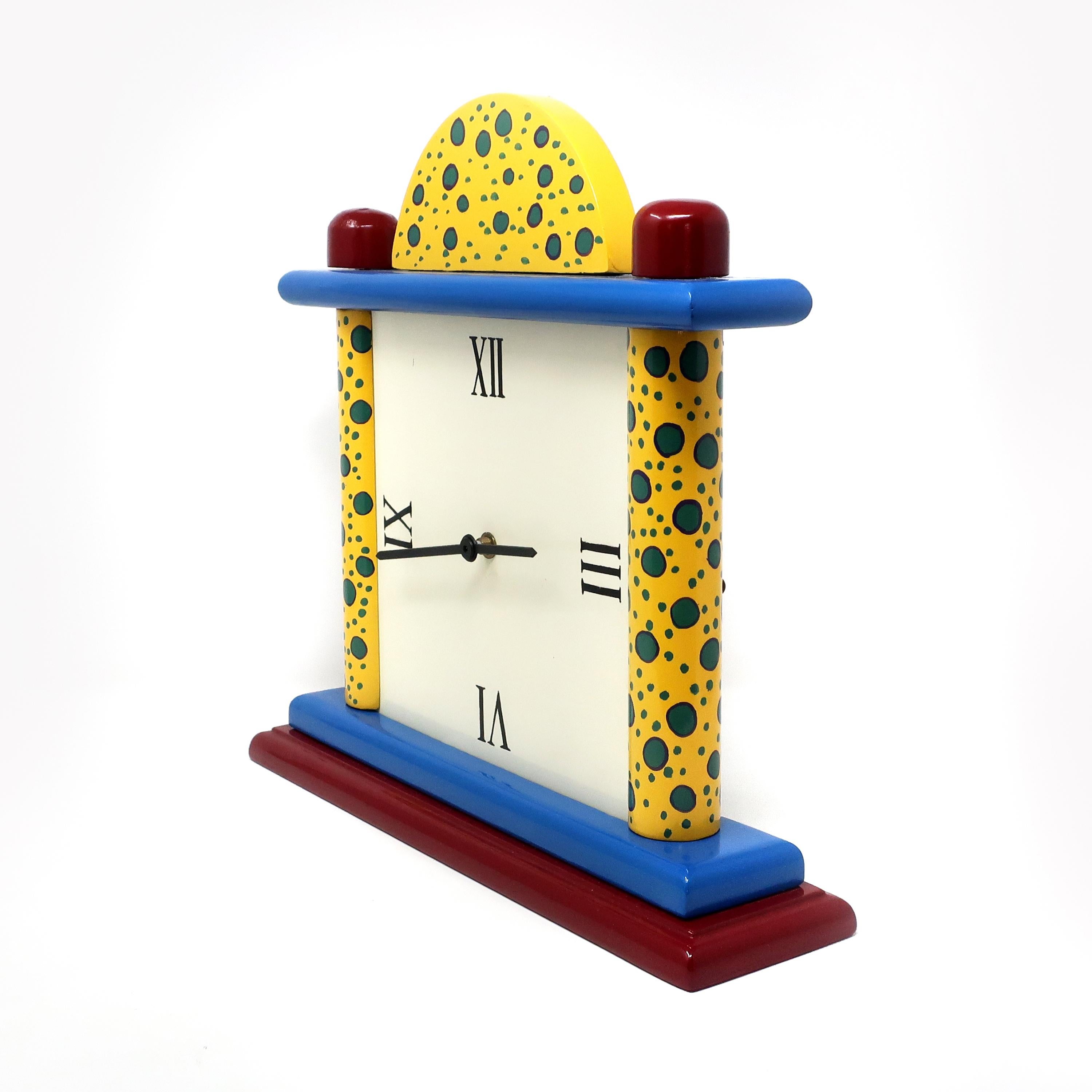 A charming multi-colored 1980s or 1990s handmade and hand painted postmodern mantle clock. Red and blue base, yellow patterned columns, and red, blue, and yellow patterned top. Has an off-white face with hand applied Roman numerals and a brand new