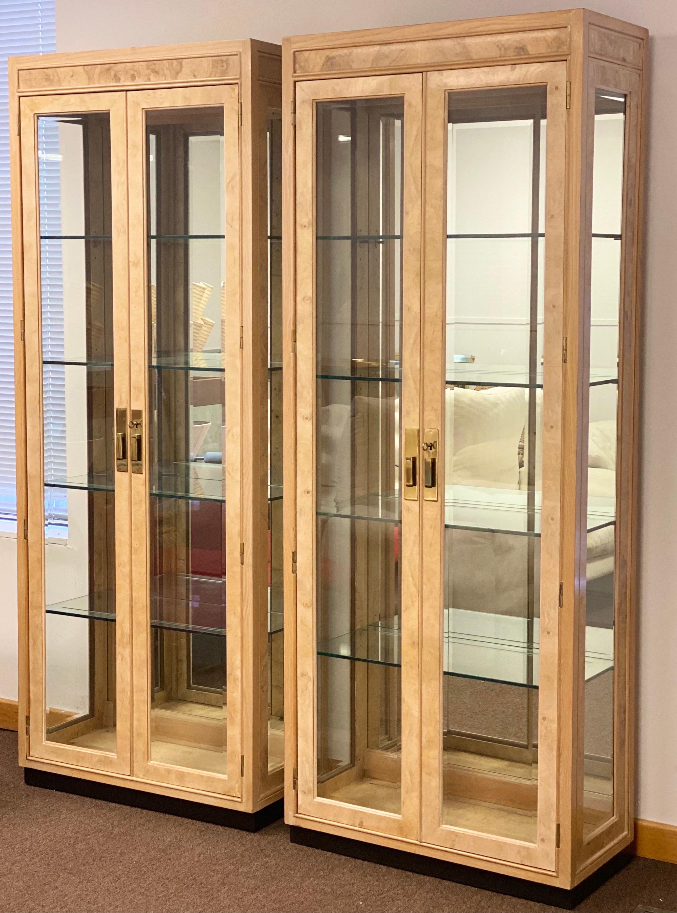 We are very pleased to offer a chic, stunning, burl wood set of display cases from the Scene Two Collection by Henredon, circa the 1980s. This gorgeous set is crafted in a warm olive ash burl wood and stands in an ebonized plinth base. These