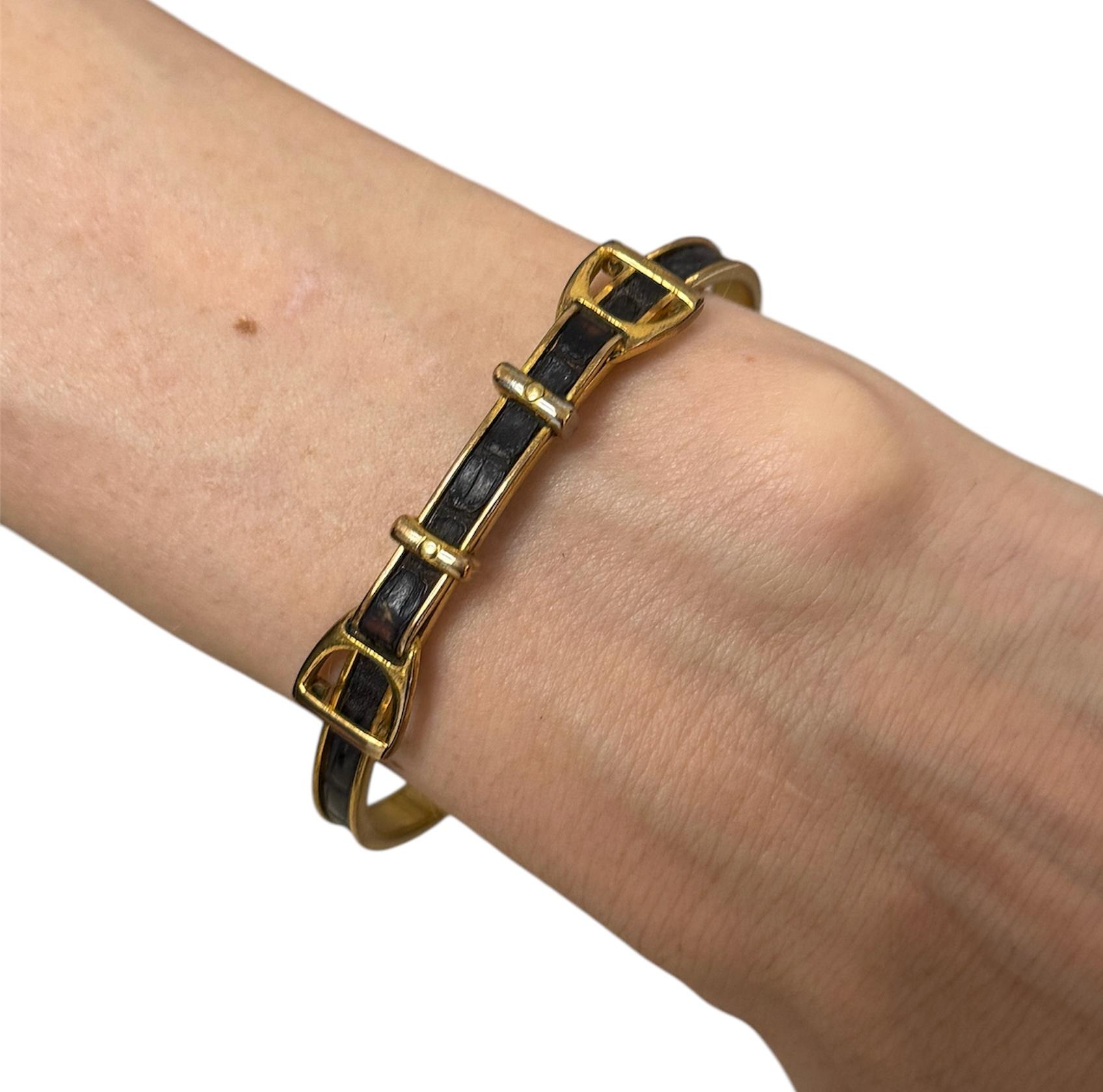 This Hermès bangle bracelet, circa 1980s, showcases the brand’s signature equestrian-inspired design. Crafted in vermeil (gold-plated sterling silver) with a textured leather inlay, the bracelet resembles a horse’s bridle with buckle and strap