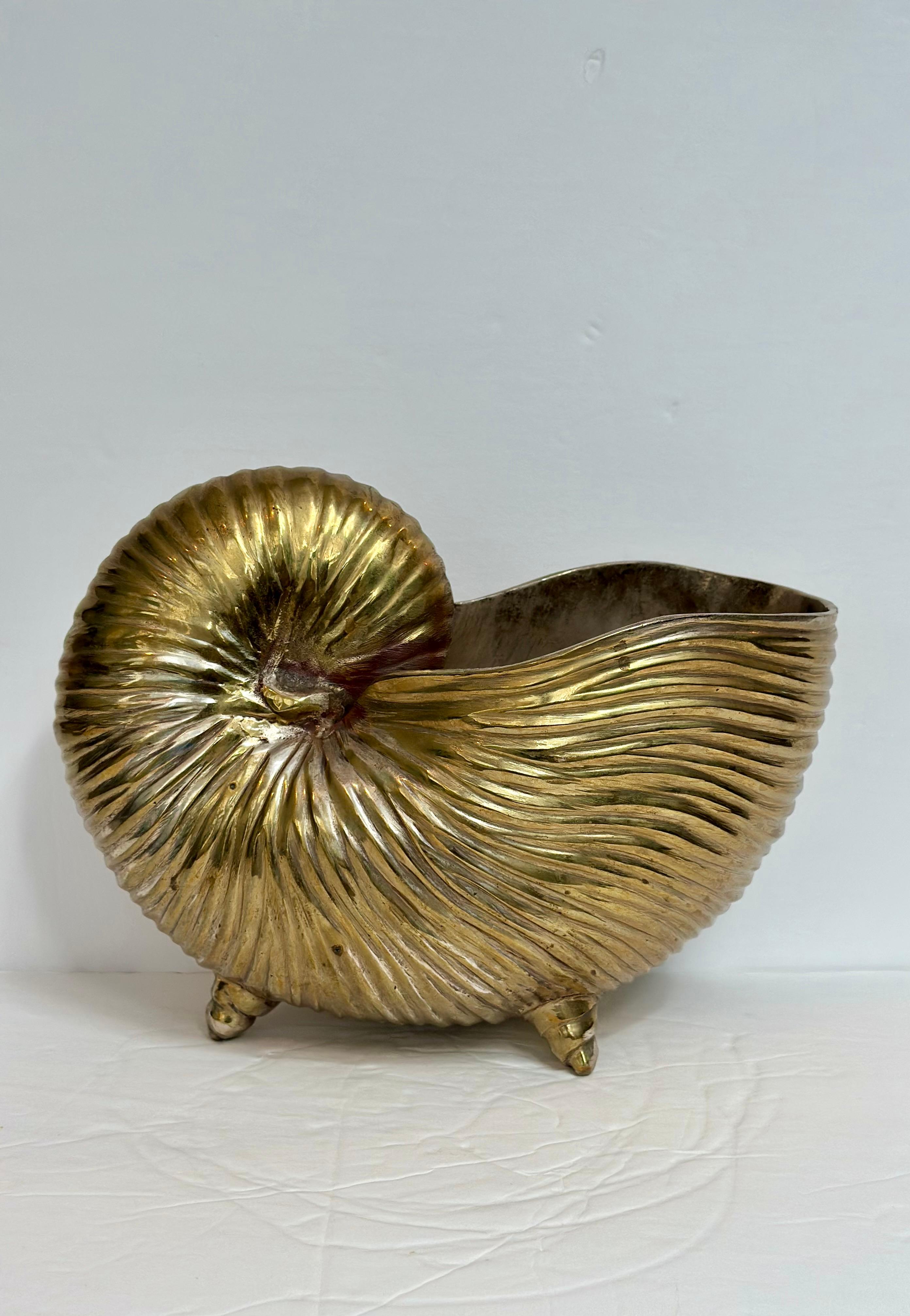 We are very pleased to offer a striking vintage brass vessel in the shape of a nautilus shell, circa the 1980s.  This sculptural piece captures the organic rhythm of the sea with its radiating ridges and lustrous golden finish.  Resting on three