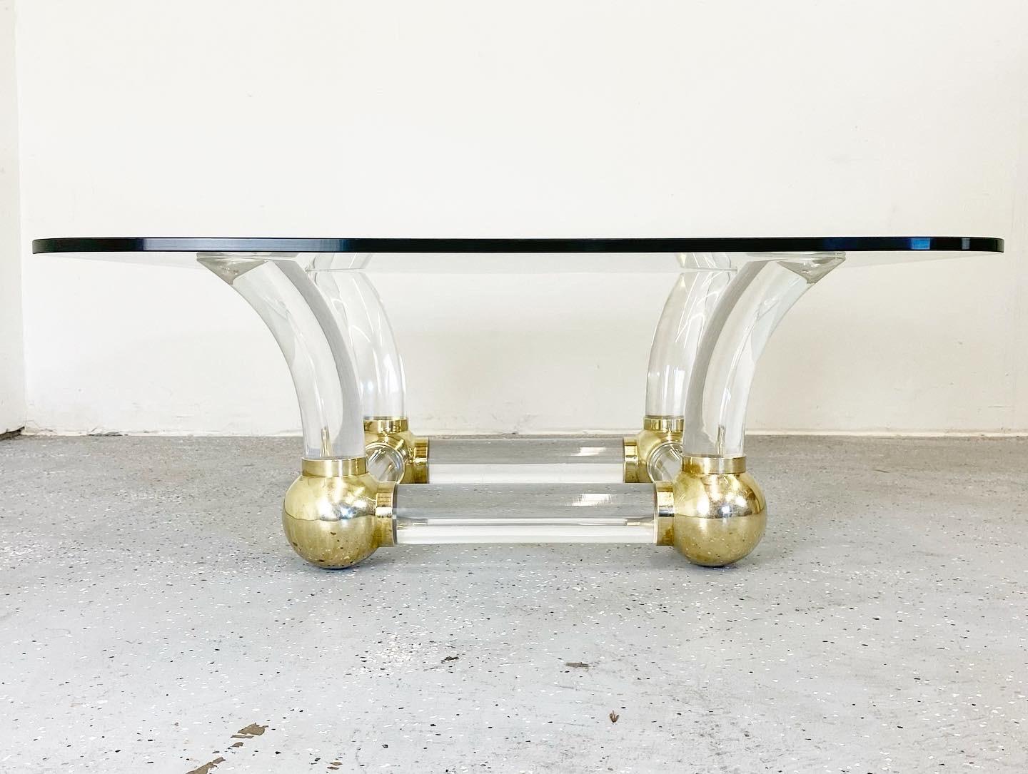 Stunning lucite tusk and brass ball coffee table. Elegant and striking; a great statement piece.

In the manner of Karl Springer.
 