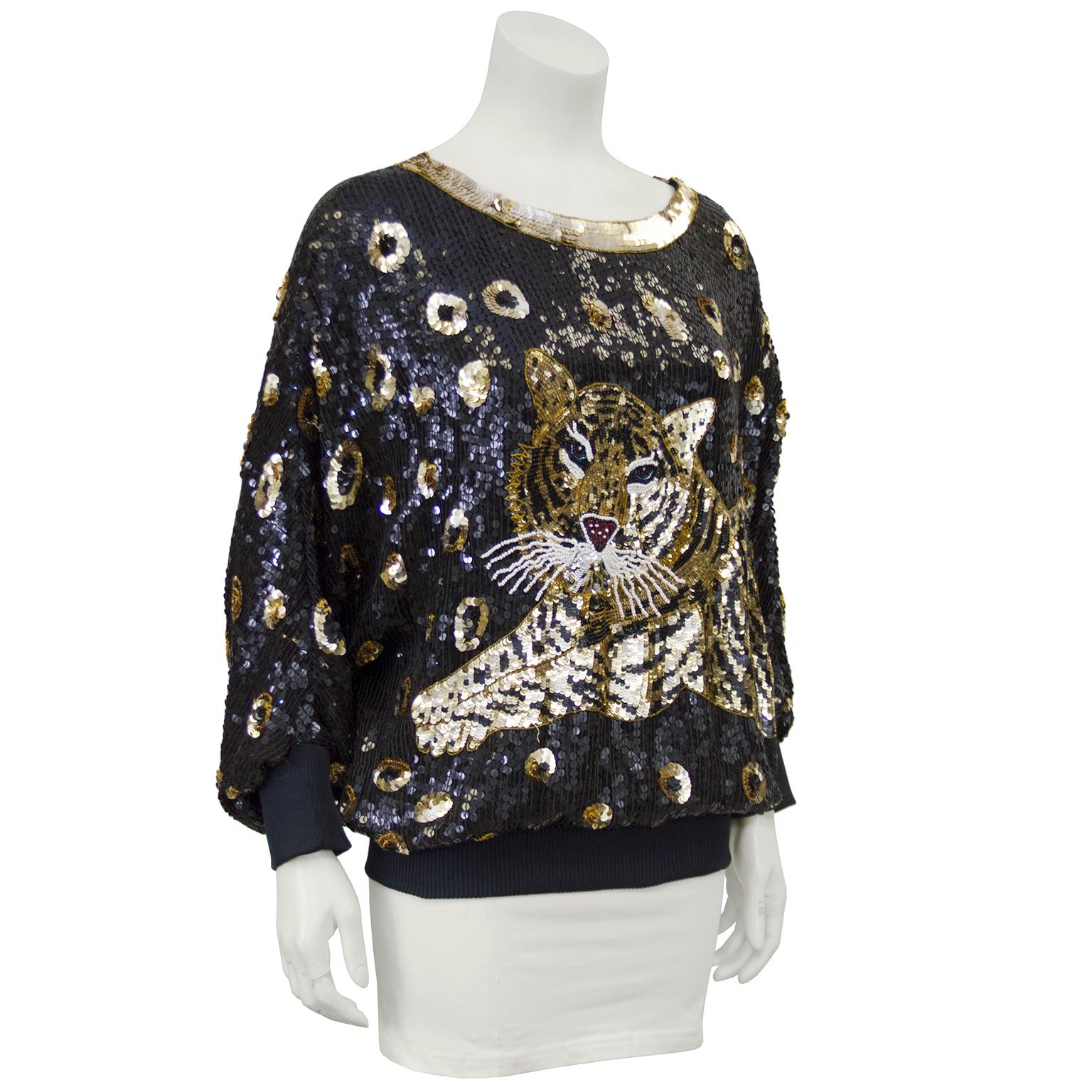 1980s sequin from the department store label, I. Magnin. The intricately sequinned top features a tiger lounging on a black back ground with irregular, cheetah  print-like gold sequin dots. The wide ribbed knit hem is meant to be worn on the hips
