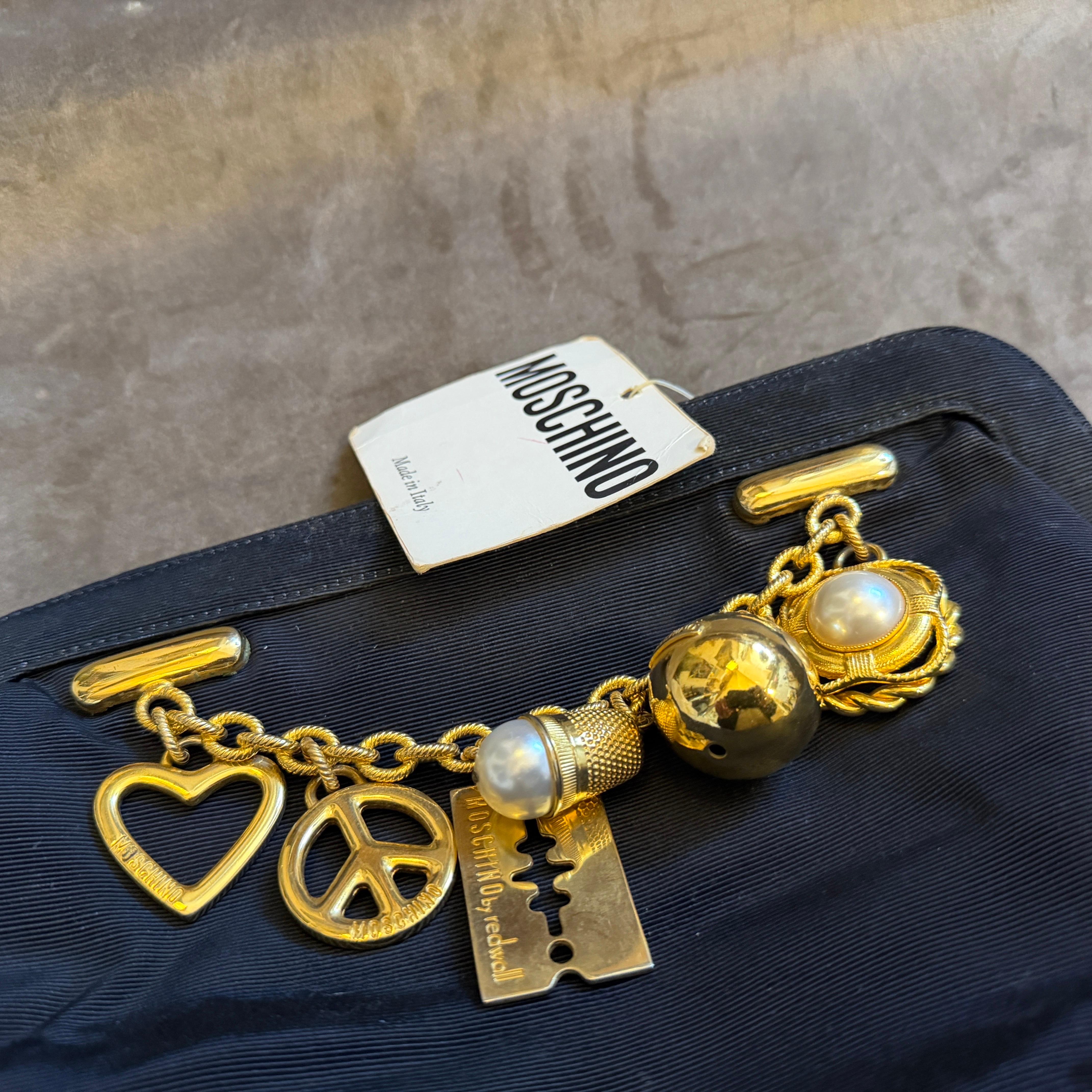 Il s'agit d'une pochette rare et de grande collection de Franco Moschino des années 1980, une pièce quintessentielle de ses premiers travaux emblématiques. Le sac est fabriqué en tissu noir et présente une forme structurée et arrondie, ainsi que des