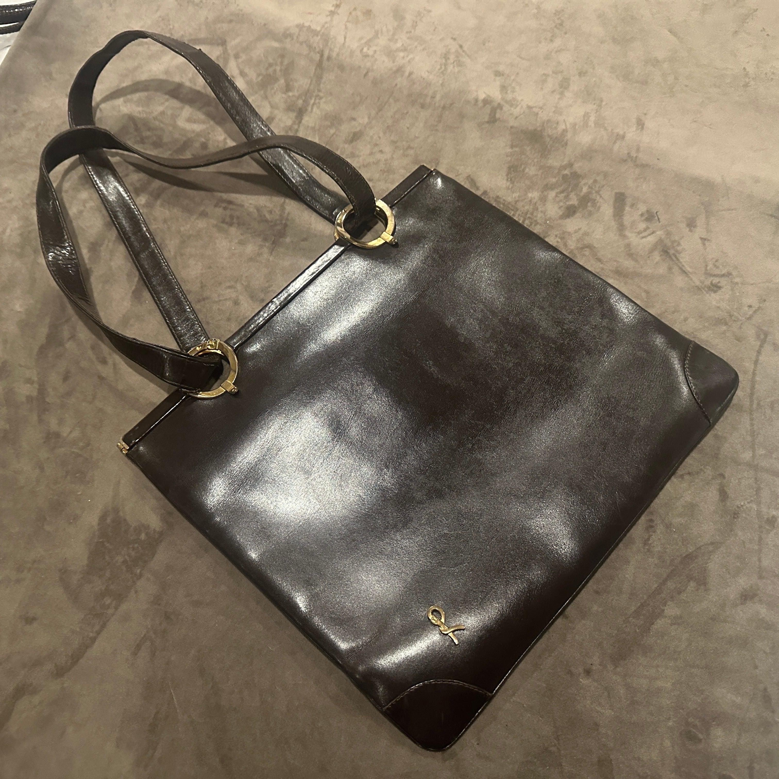 This is an elegant and highly recognizable 1980s shoulder bag by Roberta di Camerino, embodying the brand's signature blend of Italian craftsmanship and timeless design. The bag is constructed from rich, dark brown leather with a smooth, luxurious