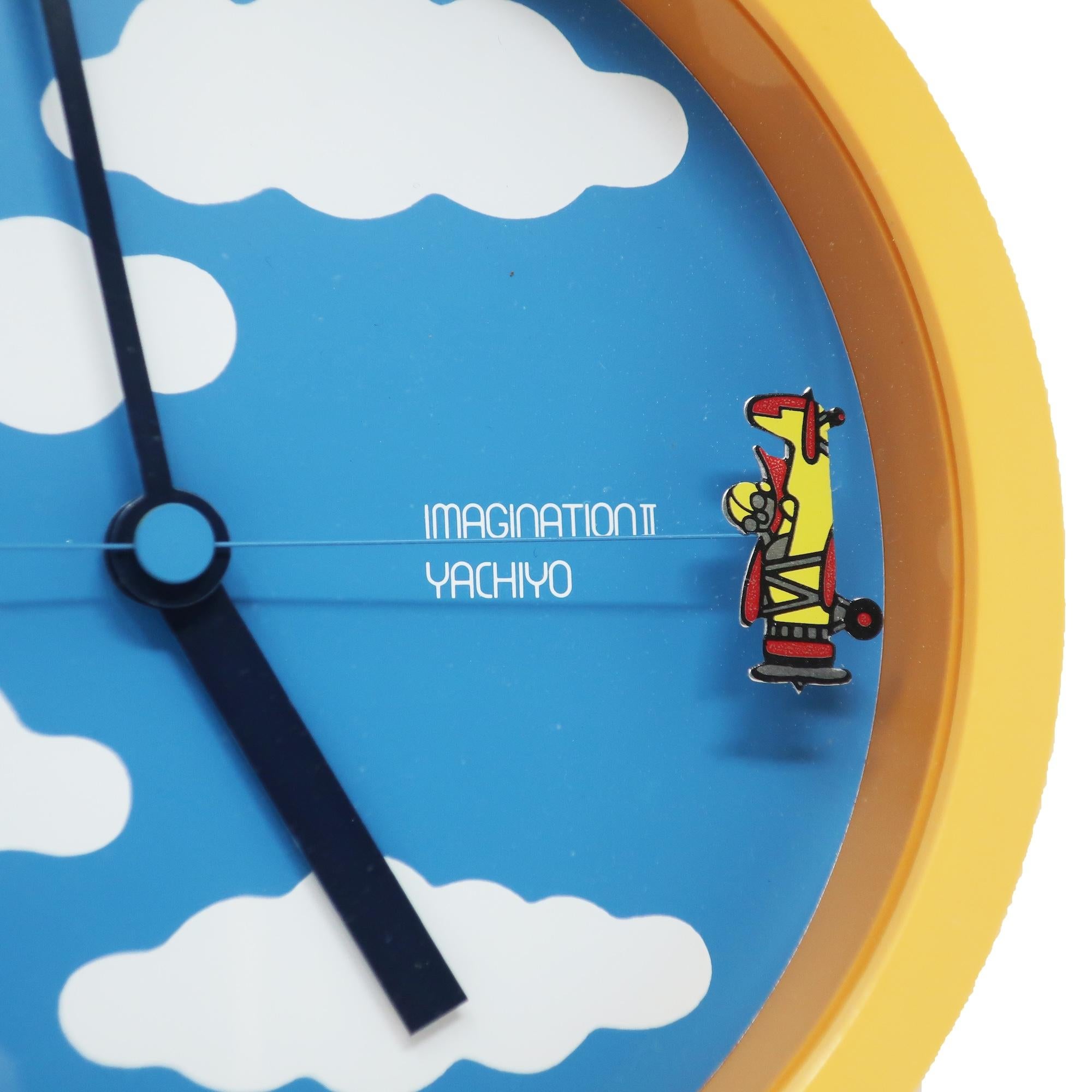 A fantastic wall clock designed by Ko Mizuyama, a prolific Japanese designer of clocks in the 1980s.  It has a round plastic case, blue face with white clouds, black hour and minute hands, and two airplanes that rotate on the second hand.

In