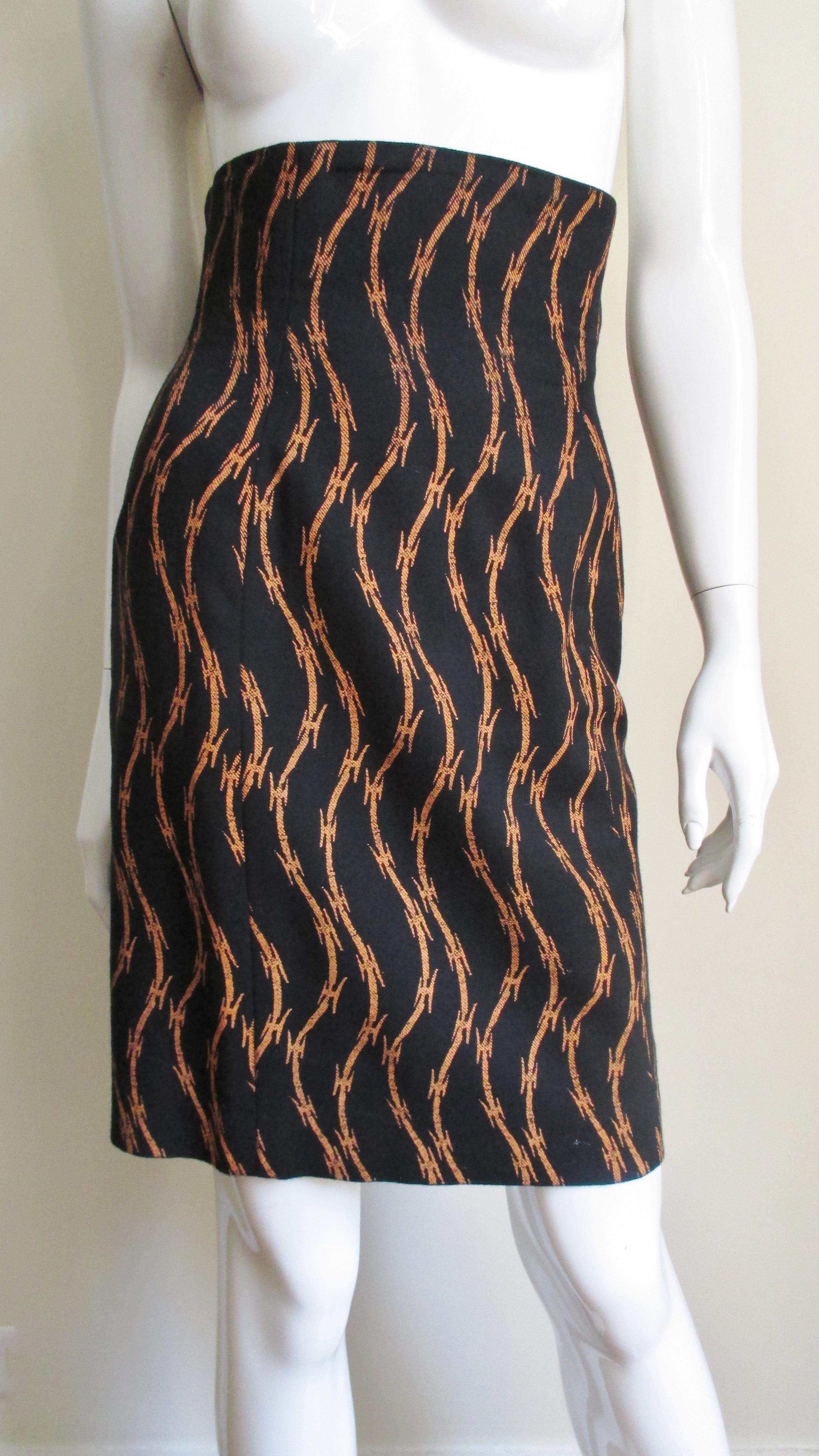 Jupe iconique en laine de Stephen Sprouse, avec des rangées verticales dorées de fils barbelés se détachant sur un fond noir.  La jupe de style crayon à taille haute est entièrement doublée et dotée d'une fermeture éclair sur le côté.
Convient aux