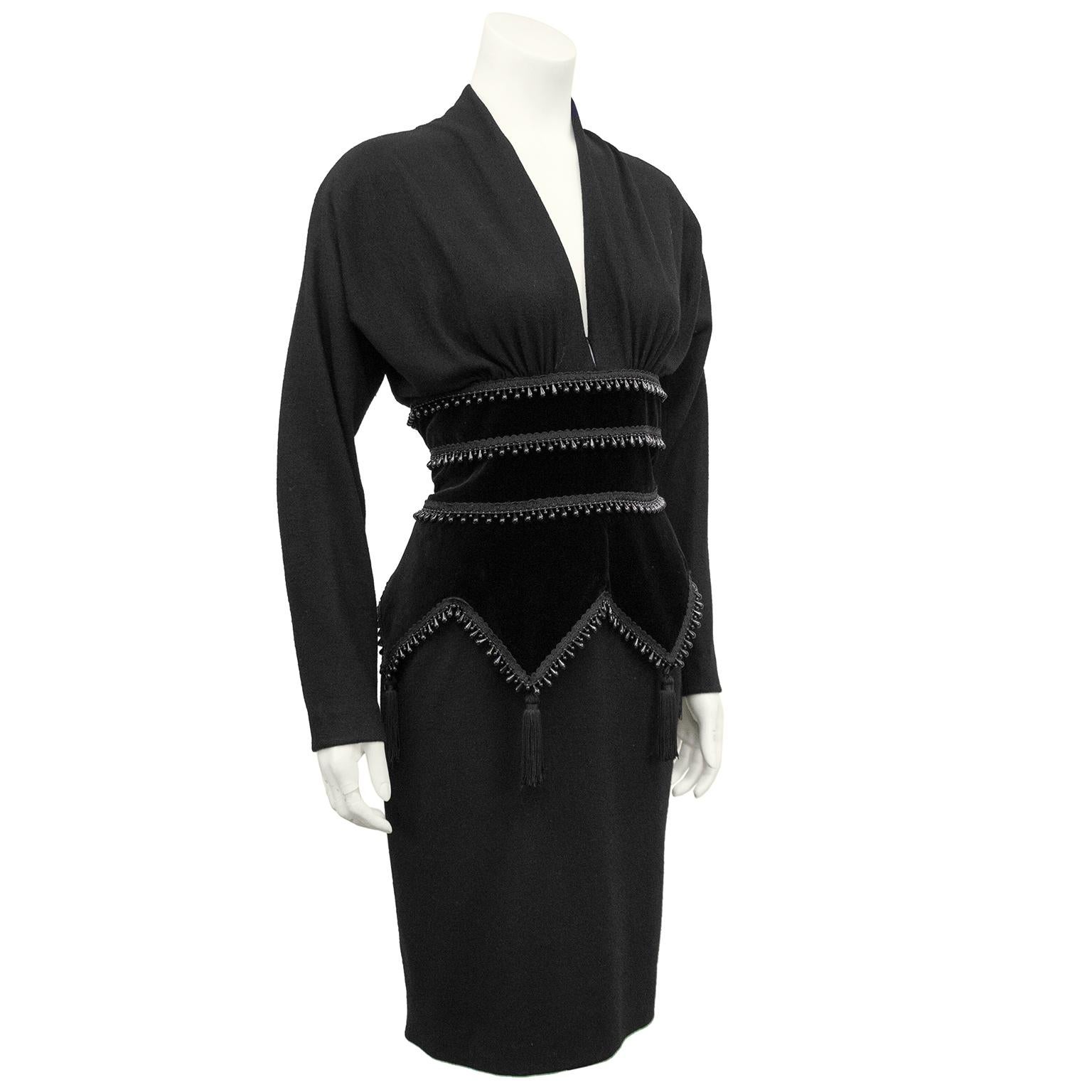 1980s Isabelle Allard black wool and velvet corset style cocktail dress. Deep v neckline with long dolman sleeves. Neckline is tacked at bottom to create a small keyhole feature. Waist features jet black cut velvet peplum-like detail with a chevron
