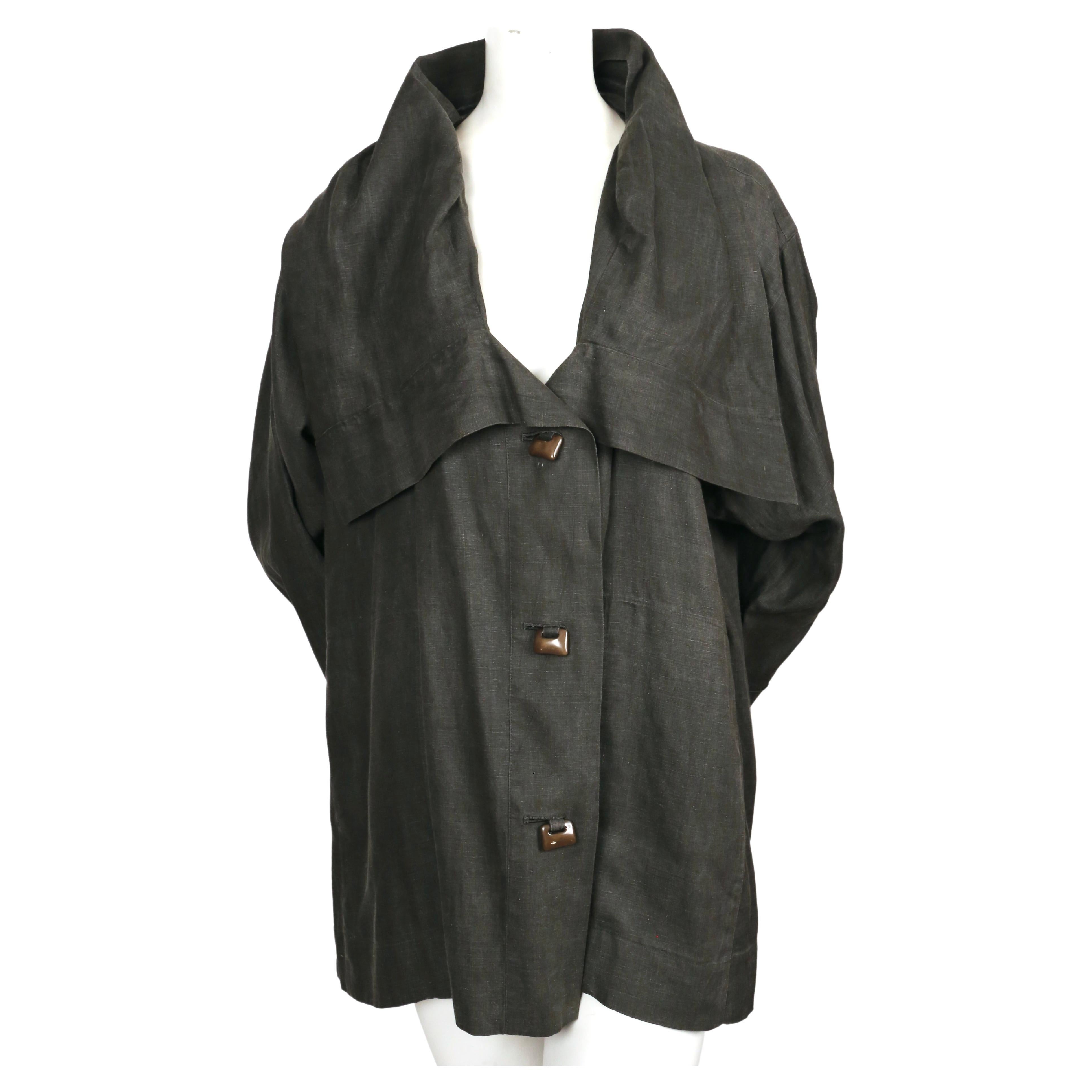 Draped, grey linen jacket with unique khaki button closure designed by Issey Miyake dating to the early 1980's. Sizing is flexible with the due to the oversized fit. Labeled a Japanese size 'M'.  Jacket has hidden slash pockets at hips and a stand