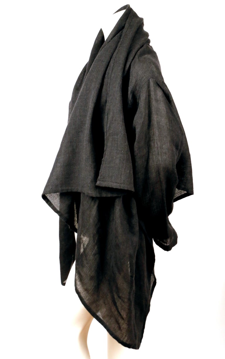 Lightweight, charcoal grey, woven wool wrap jacket with a draped, asymmetrical fit designed by Issey Miyake Plantation. No size is indicated however this fits most sizes due to the design. No fabric content label is present. Made in Japan. Very good