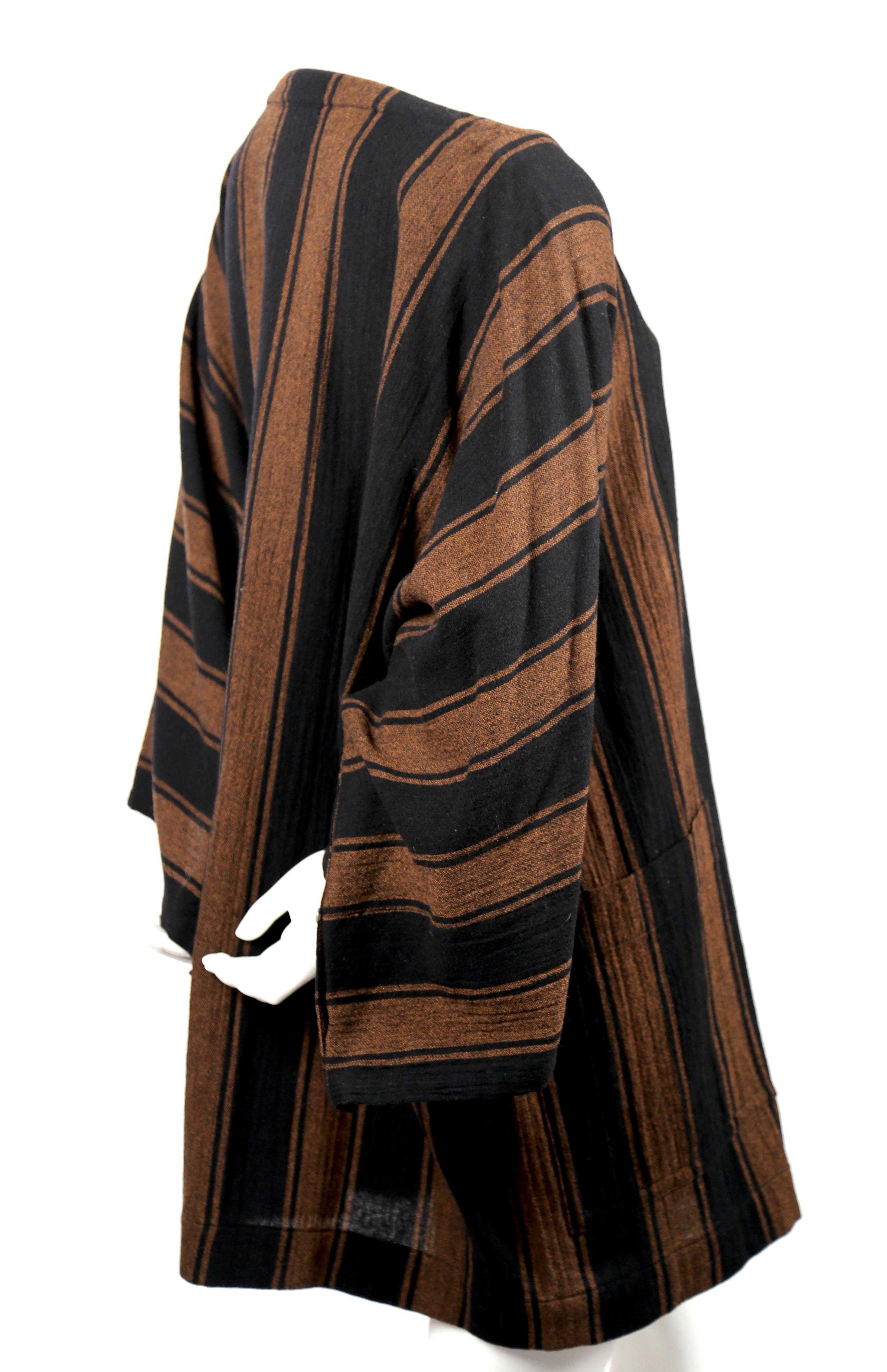 Black and rust striped wool tunic dress with wrap around patch pockets and interesting button detail on undersides of arms designed by Issey Miyake for his 'Plantation' line dating to the 1980's.  Labeled a Japanese size S however due to the