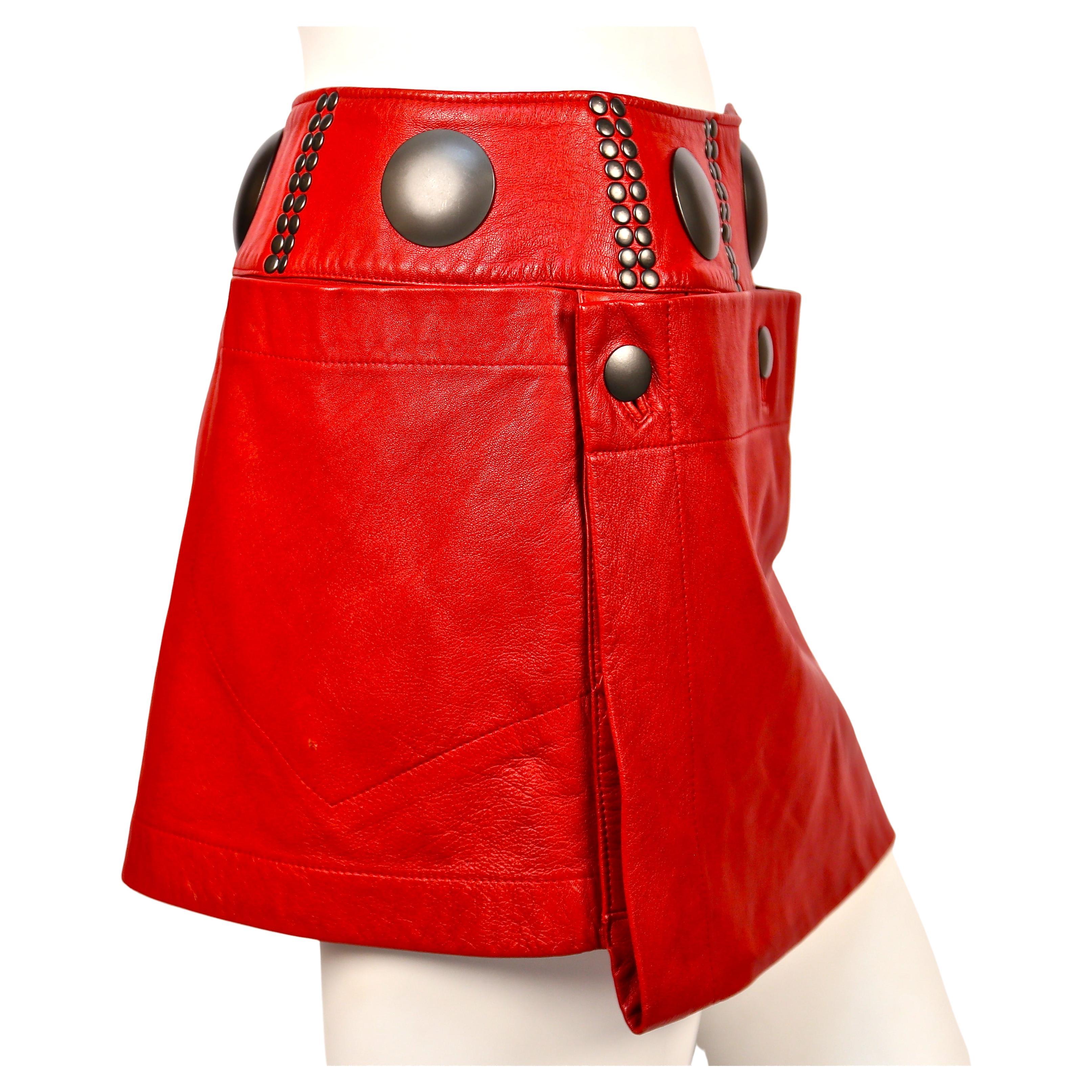 Vivid red leather mini skirt with oversized gunmetal studs from Issey Miyake dating to the 1980's. Labeled a size medium however this skirt best fits a size small or medium. Approximate measurements: 28