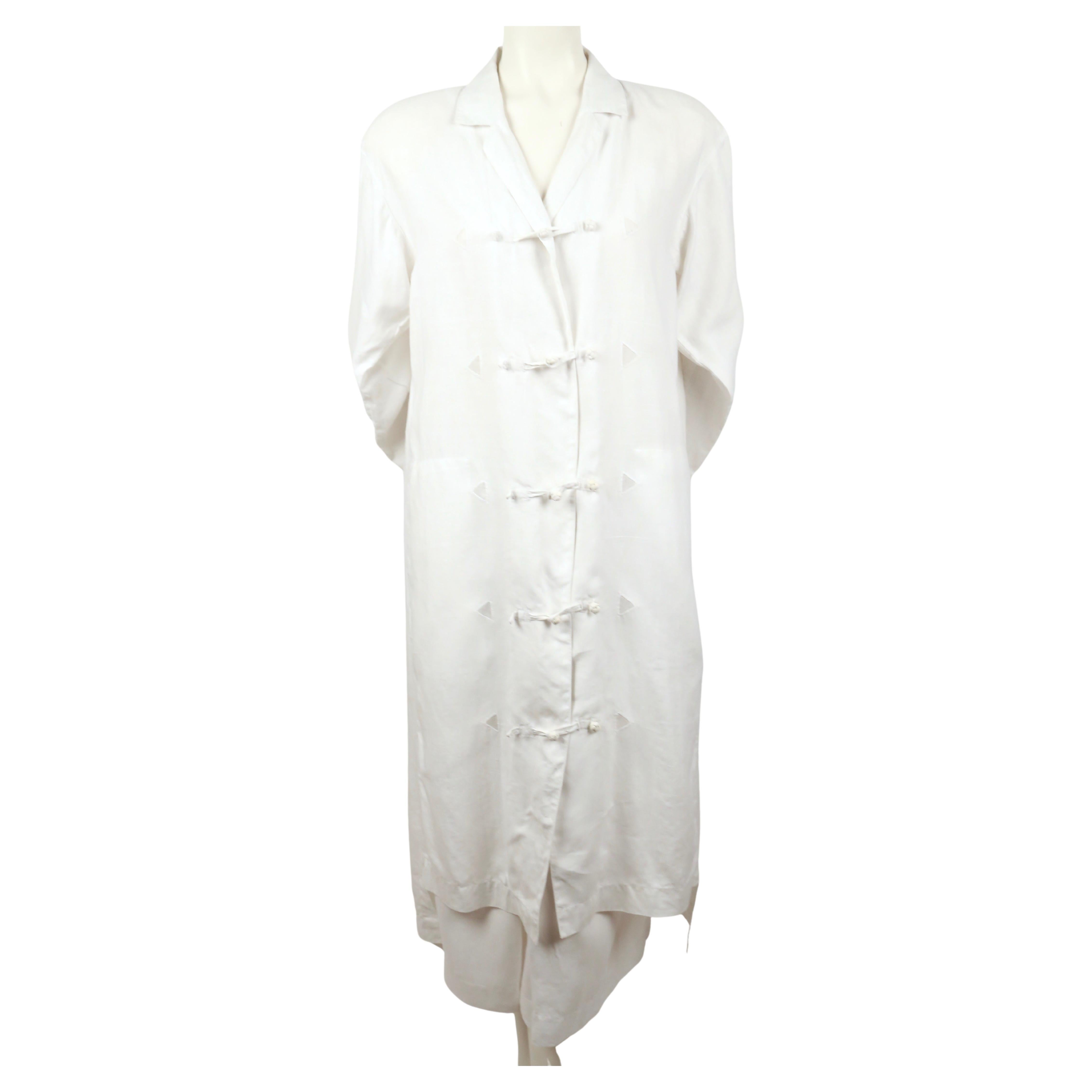 White, linen duster jacket and matching skirt with knotted button closure designed by Issey Miyake dating to the 1980's. Jacket is labeled a small and skirt is labeled a medium. Duster measure approximately: shoulder 20