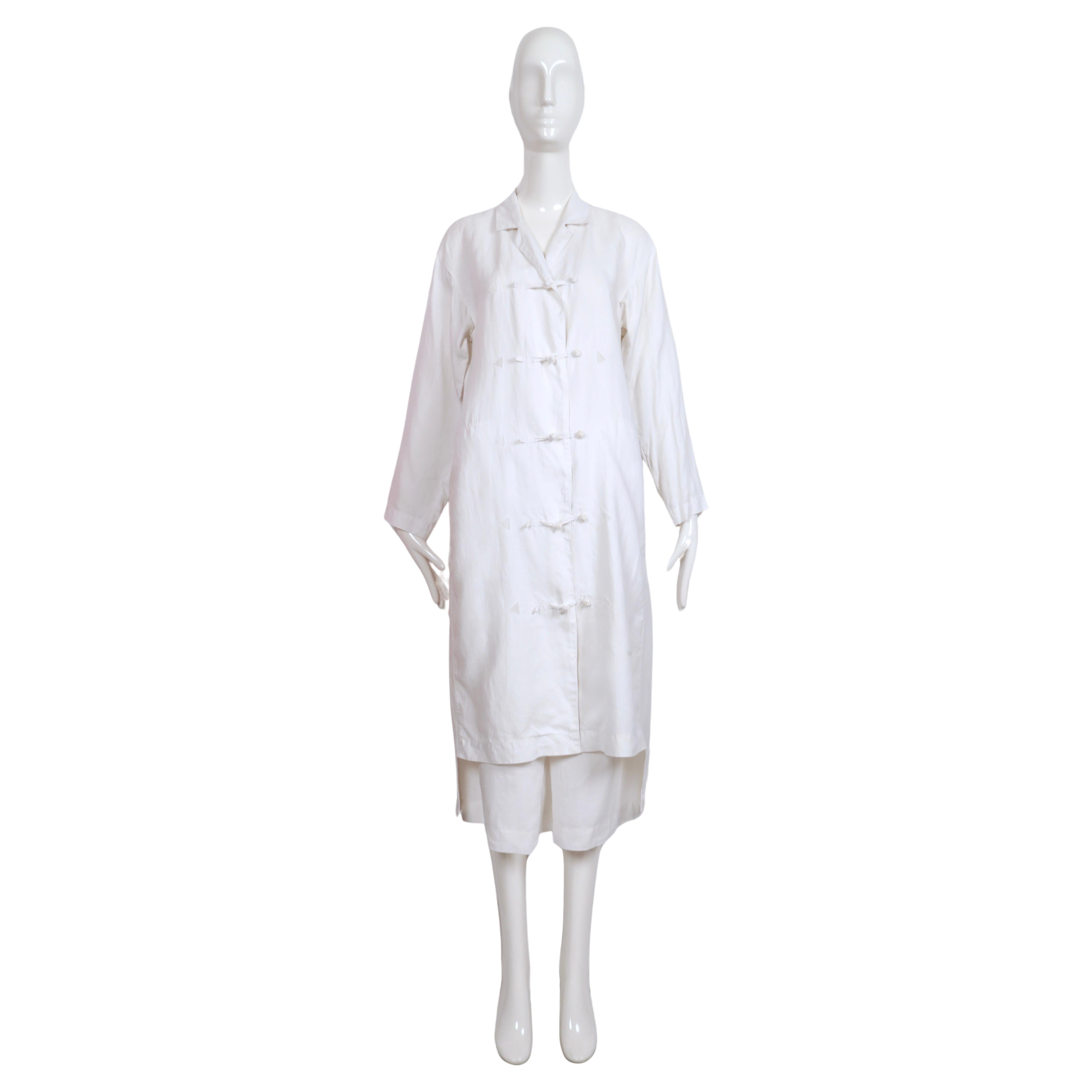 Stunning white, linen duster jacket and matching skirt with knotted button closure and sheer triangular inserts designed by Issey Miyake dating to the 1980's. Jacket has a a very unique cut at hem to show the skirt from front but conceal it from the