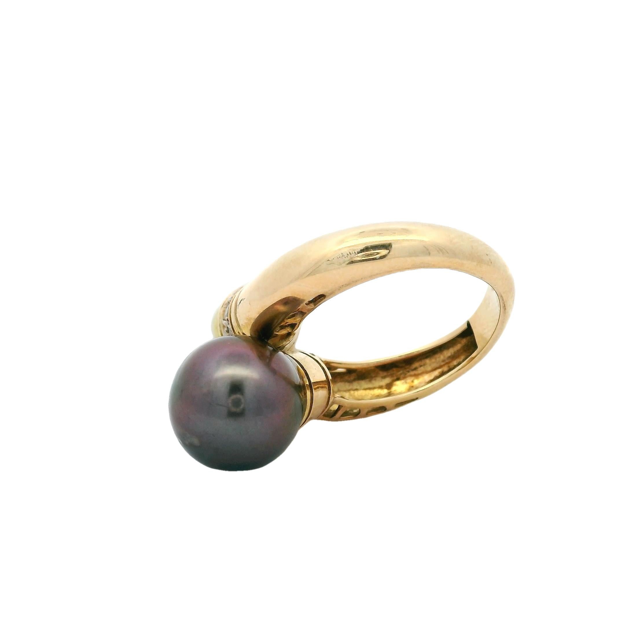 Un elegante e scultoreo anello degli anni '80 realizzato in Italia in oro giallo 18 carati, con due splendide perle dei Mari del Sud, una bianca e una nera, incastonate in un design a bypass accentuato da una fascia di diamanti taglio brillante per