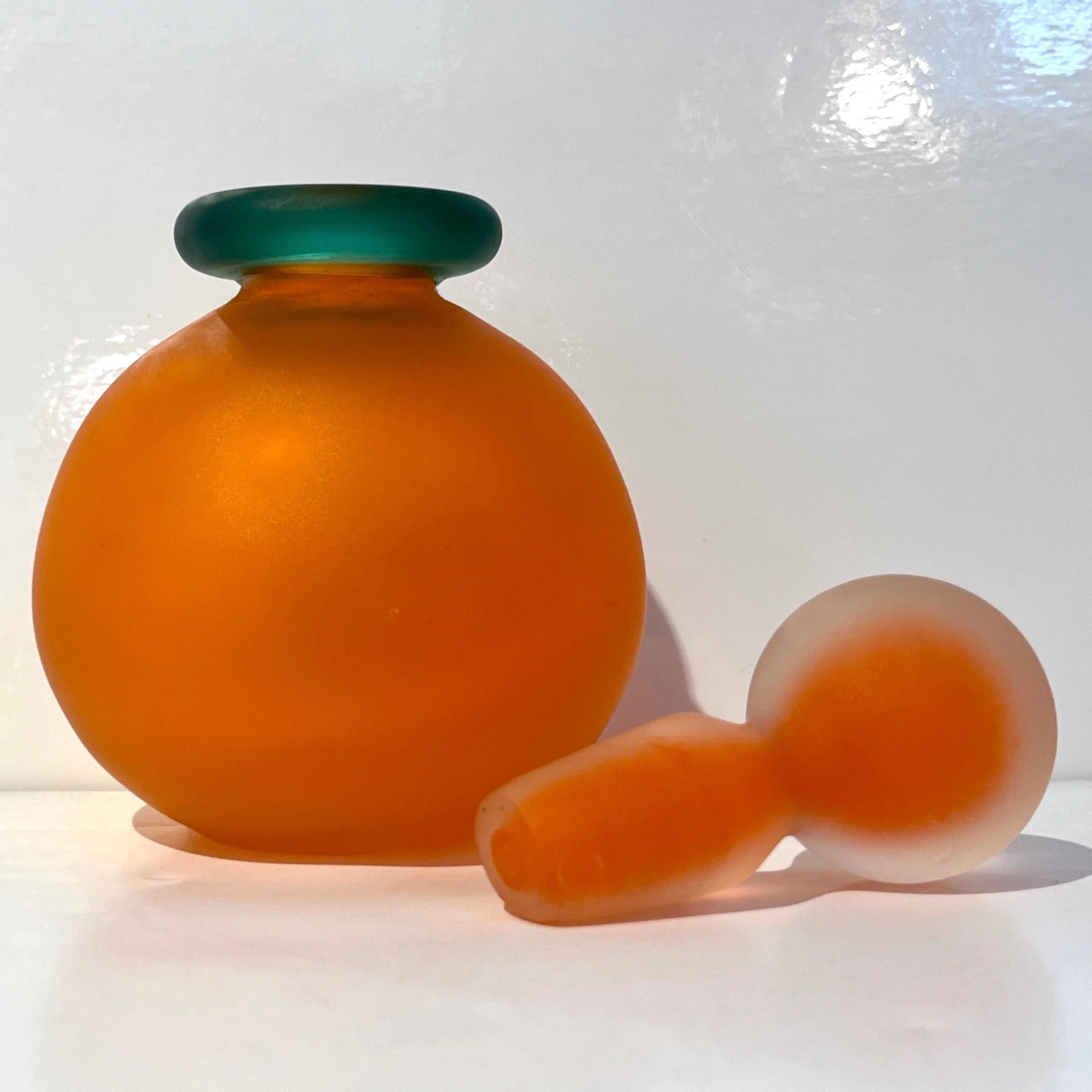 An early 1980s Venitian bottle in Frosted Murano glass in a vibrant orange and emerald green with an elegant sophisticated stopper worked with the frosted and Sommerso technique adds an intriguing side to this decorative object, typical of the work