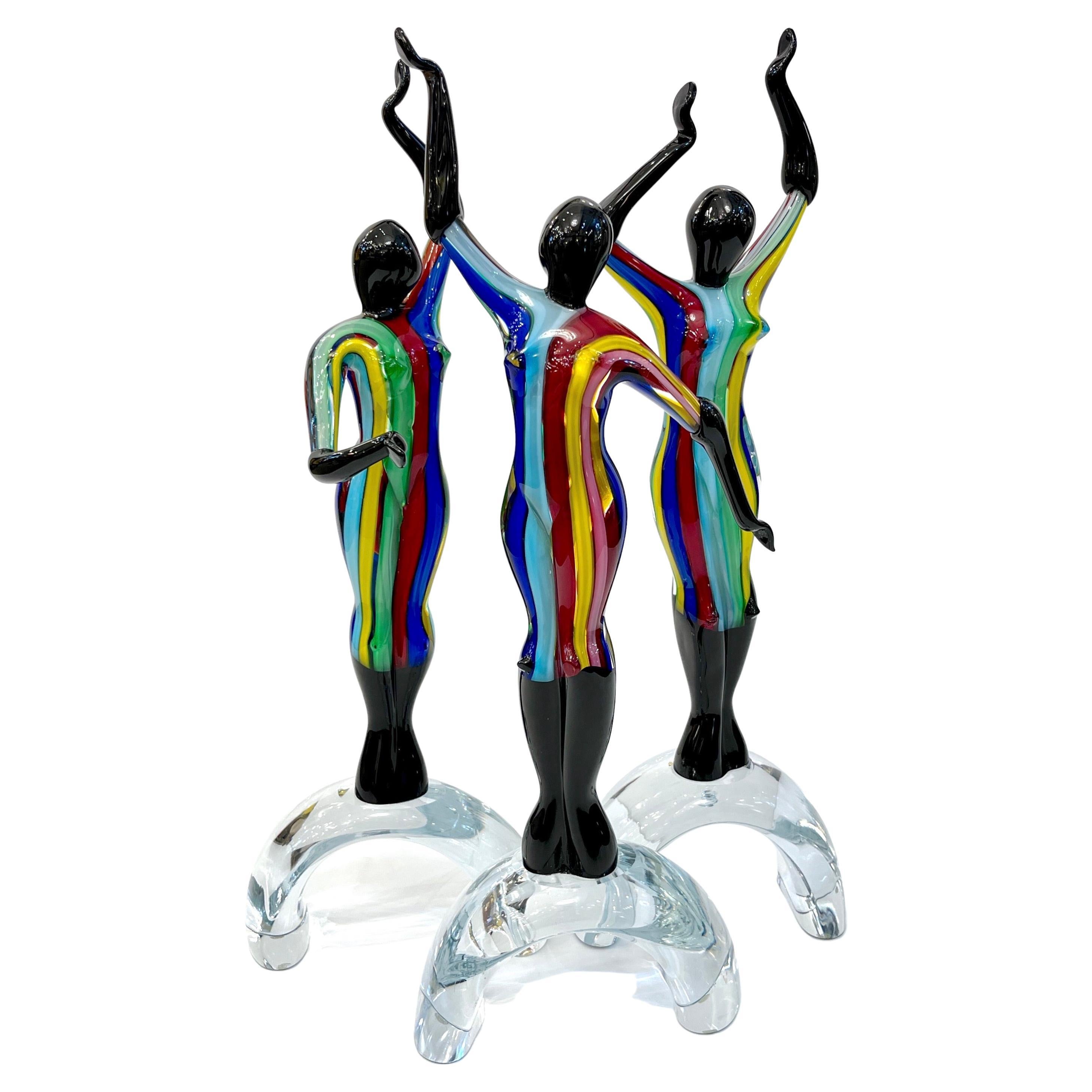 Diese bezaubernden Skulpturen aus Murano-Glas, signiert mit Formia Vetri di Murano Glass Made in Italy, stellen ein anmutiges Trio stilisierter Ballerinen dar, die mitten im Tanz stehen und dabei sowohl Bewegung als auch Einheit verkörpern. Jede