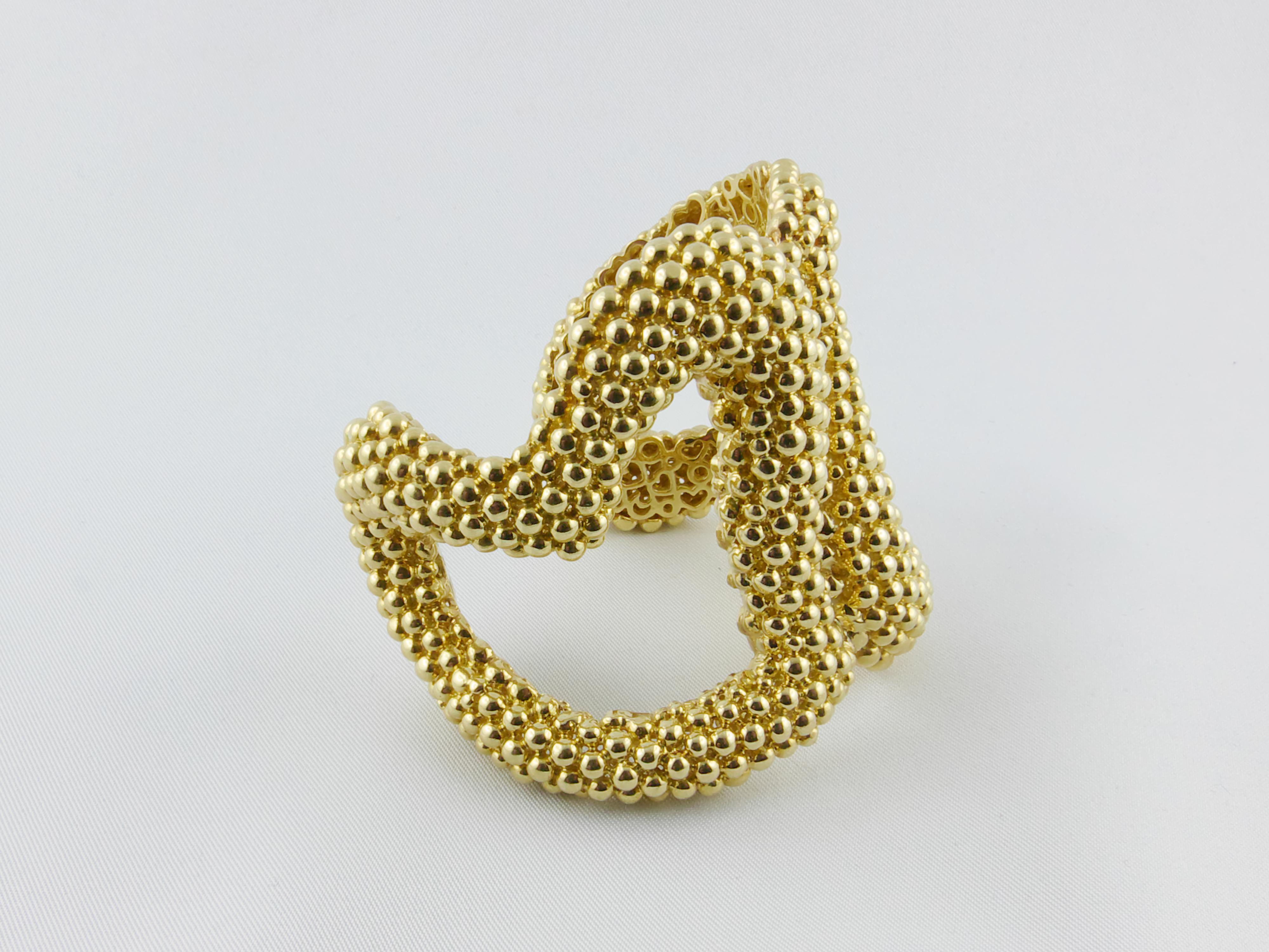 Attractive, unconventional and asymmetrical 1980s double-heart Cuff finely crafted in Italy in 18k polished solid Yellow Gold .
This modern and intriguing Bracelet is composed of polished Gold spheres  creating a textured “couscous” design. The