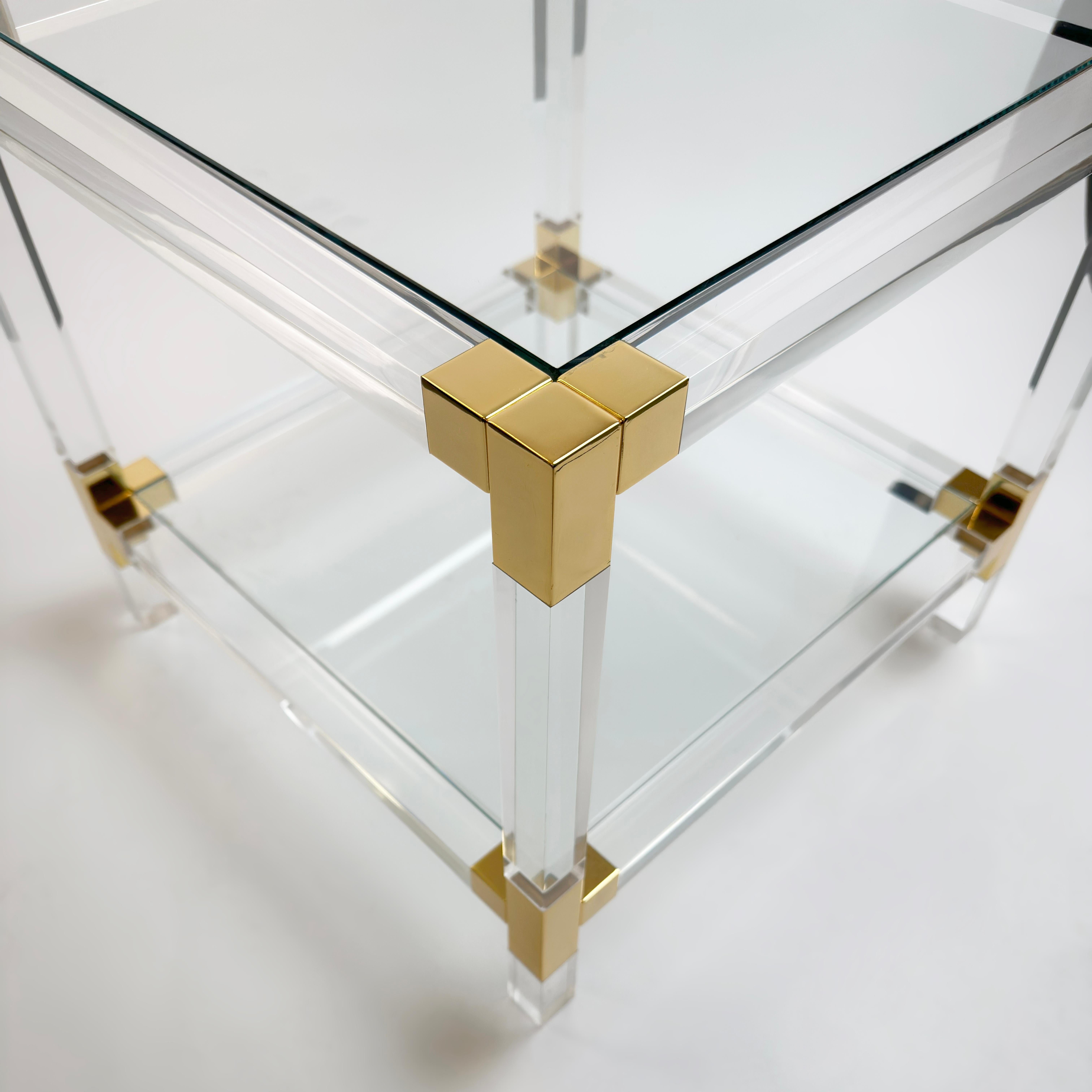 A square Italian Lucite and gold-plated metal side table dating from the 1980s, this piece captures the restrained opulence of Hollywood Regency design while maintaining a minimalist, modernist clarity.

Constructed from solid Lucite, the frame is